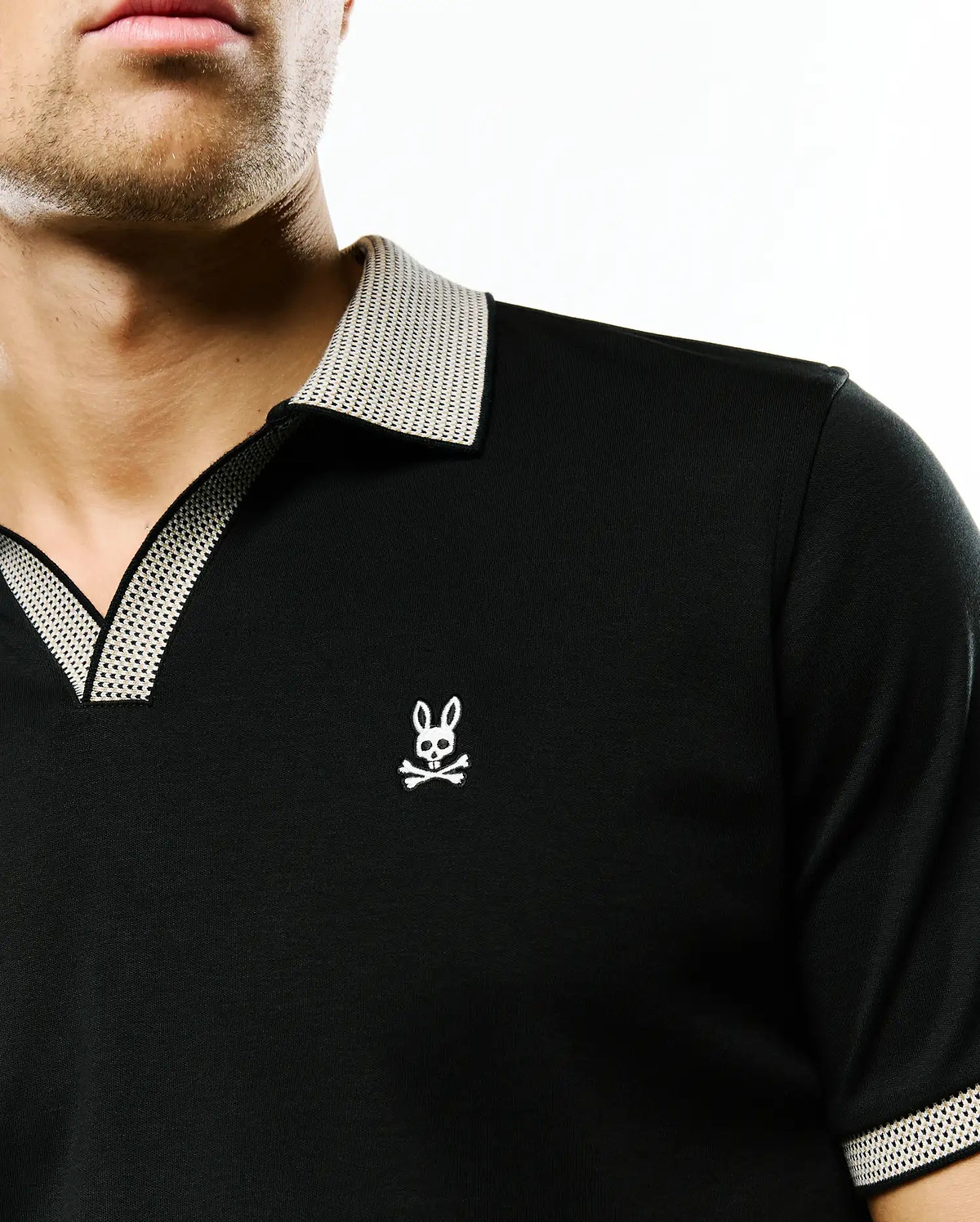Black jersey Men's Teddy Johnny Collar Polo with a classic fit, featuring a white textured Johnny collar, matching sleeve trim, and a small embroidered Psycho Bunny skull logo on the left chest. (2)