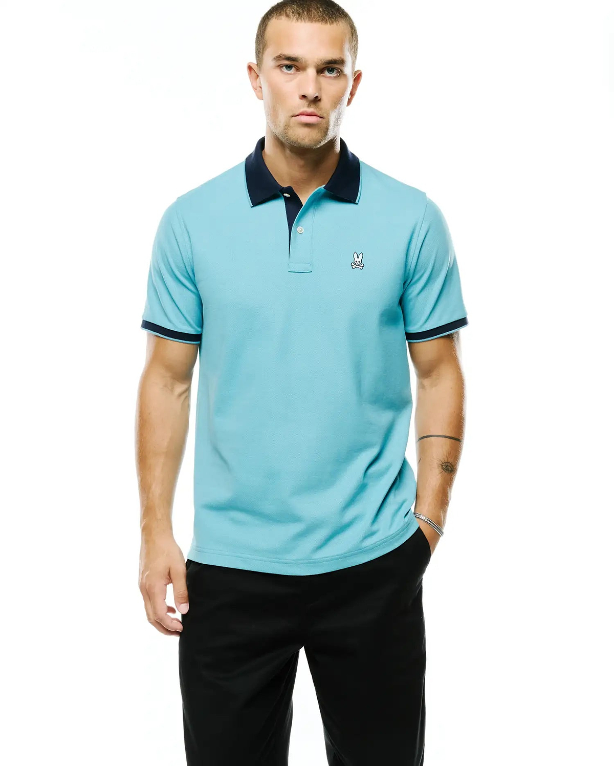 Men's Klaus Pique Polo in aqua blue, a classic fit pique knit polo with navy collar and cuffs, featuring a small embroidered white Psycho Bunny skull logo on the left chest. (3)