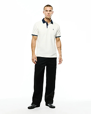 Men's Klaus Pique Polo in off-white, featuring a navy blue collar, light blue and navy striped ribbed cuffs, and a small embroidered Psycho Bunny skull logo on the left chest. (4)