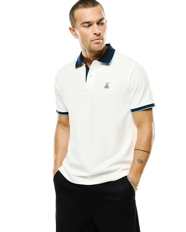Men's Klaus Pique Polo in off-white, featuring a navy collar with light blue trim, matching striped sleeve cuffs, and a small embroidered Psycho Bunny skull logo on the left chest. (1)
