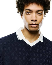 Mens Garry Jacquard Johnny Collar Polo in navy, featuring an all-over jacquard knit pattern of Psycho Bunny skull logos and P letters in a diamond grid, with a white Johnny collar and navy striped trim.