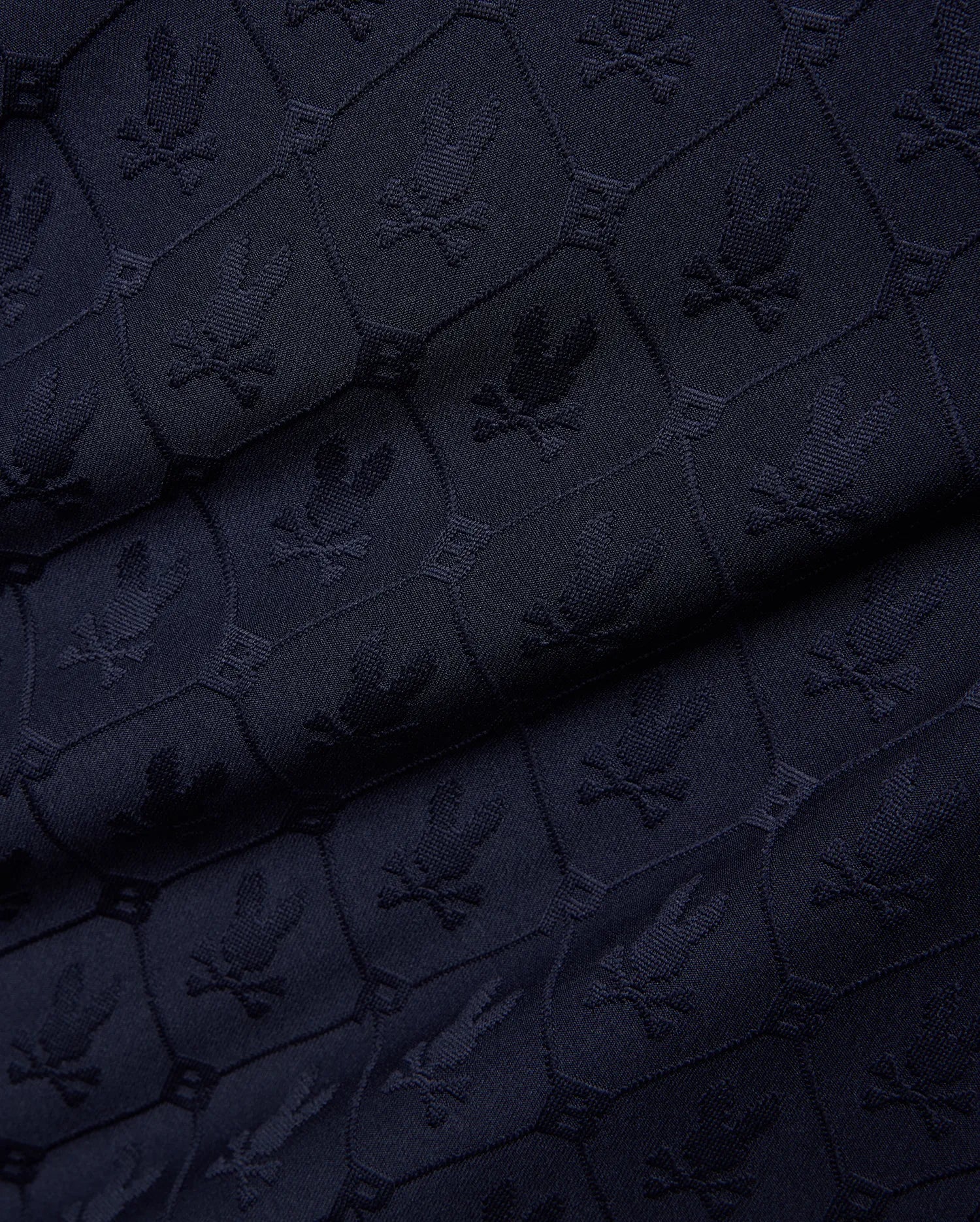 Mens Garry Jacquard Johnny Collar Polo in dark navy, featuring an all-over tone-on-tone jacquard knit pattern of the iconic Psycho Bunny skull logo within hexagonal shapes.