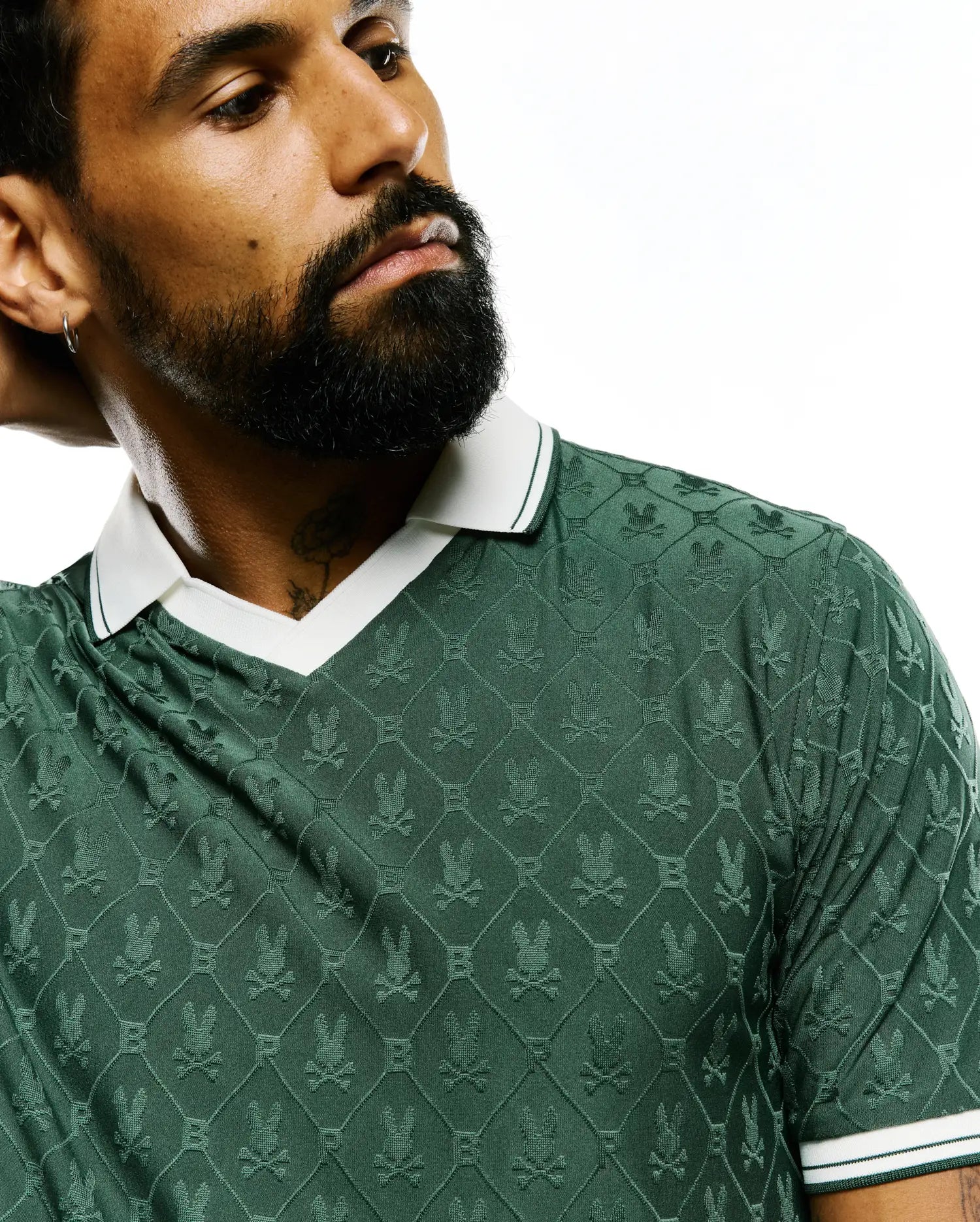 Mens Garry Jacquard Johnny Collar Polo in deep green, featuring an all-over textured Psycho Bunny skull logo pattern, with a white Johnny collar and ribbed cuffs accented by green stripes. (5)