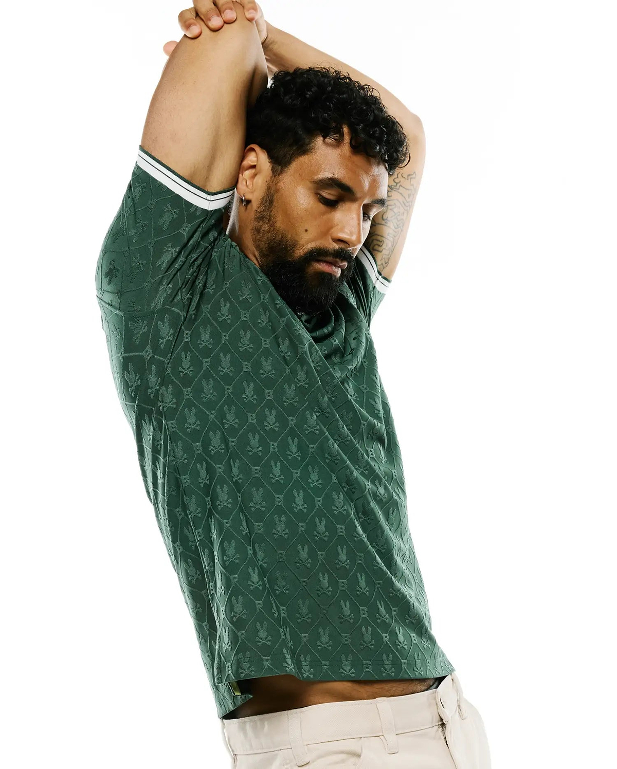 Mens Garry Jacquard Johnny Collar Polo in dark green, featuring an all-over jacquard Psycho Bunny skull logo pattern in a diamond grid, slim fit, and white double-stripe trim on sleeve cuffs. (4)