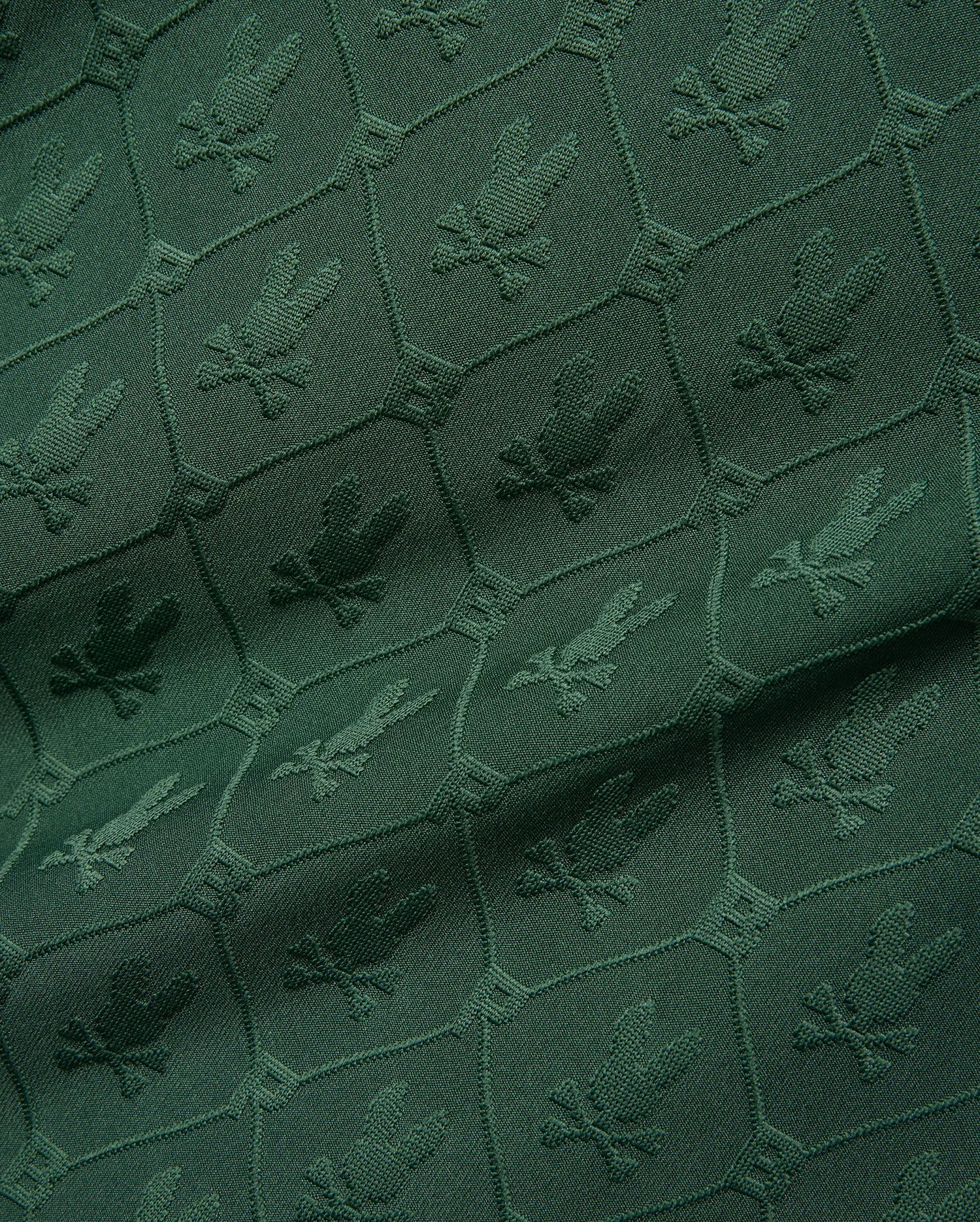 Mens Garry Jacquard Johnny Collar Polo in deep green, featuring an all-over tonal jacquard pattern of the iconic Psycho Bunny skull logo within a hexagonal grid. (9)