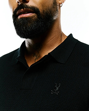 Black Mens Leroy Long Sleeve Knit Polo with a textured pique-like fabric, featuring a small, tonal embroidered Psycho Bunny skull logo on the left chest.