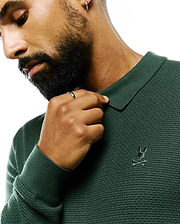 Mens Leroy Long Sleeve Knit Polo in deep forest green, featuring a textured knit fabric, ribbed collar and cuffs, and a small, tonal embroidered Psycho Bunny skull logo on the left chest.