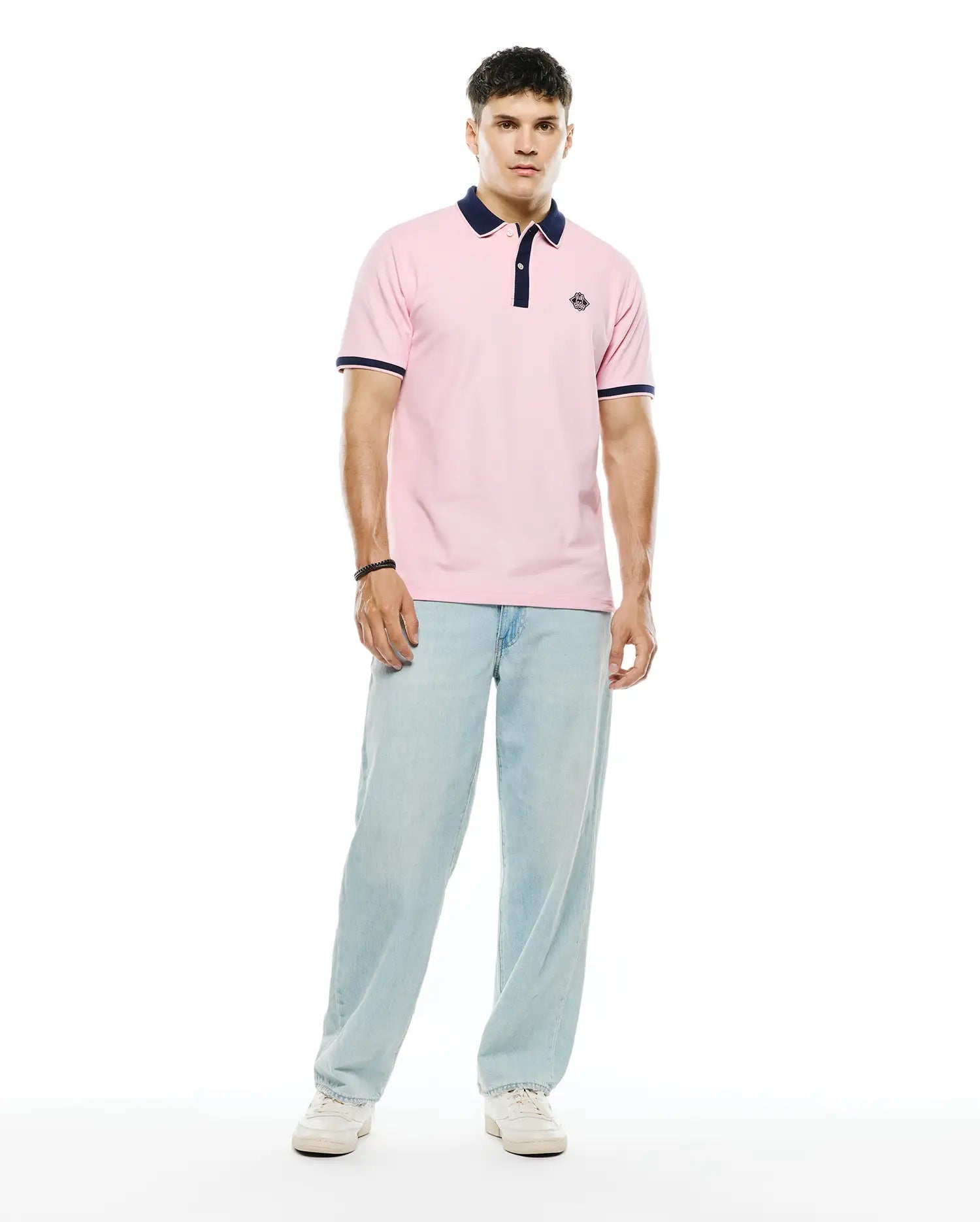 Mens Robin Pique Polo in classic fit pink pique fabric, featuring a navy blue collar, two-button placket, navy and white striped ribbed cuffs, and a small embroidered Psycho Bunny skull logo on the left chest.