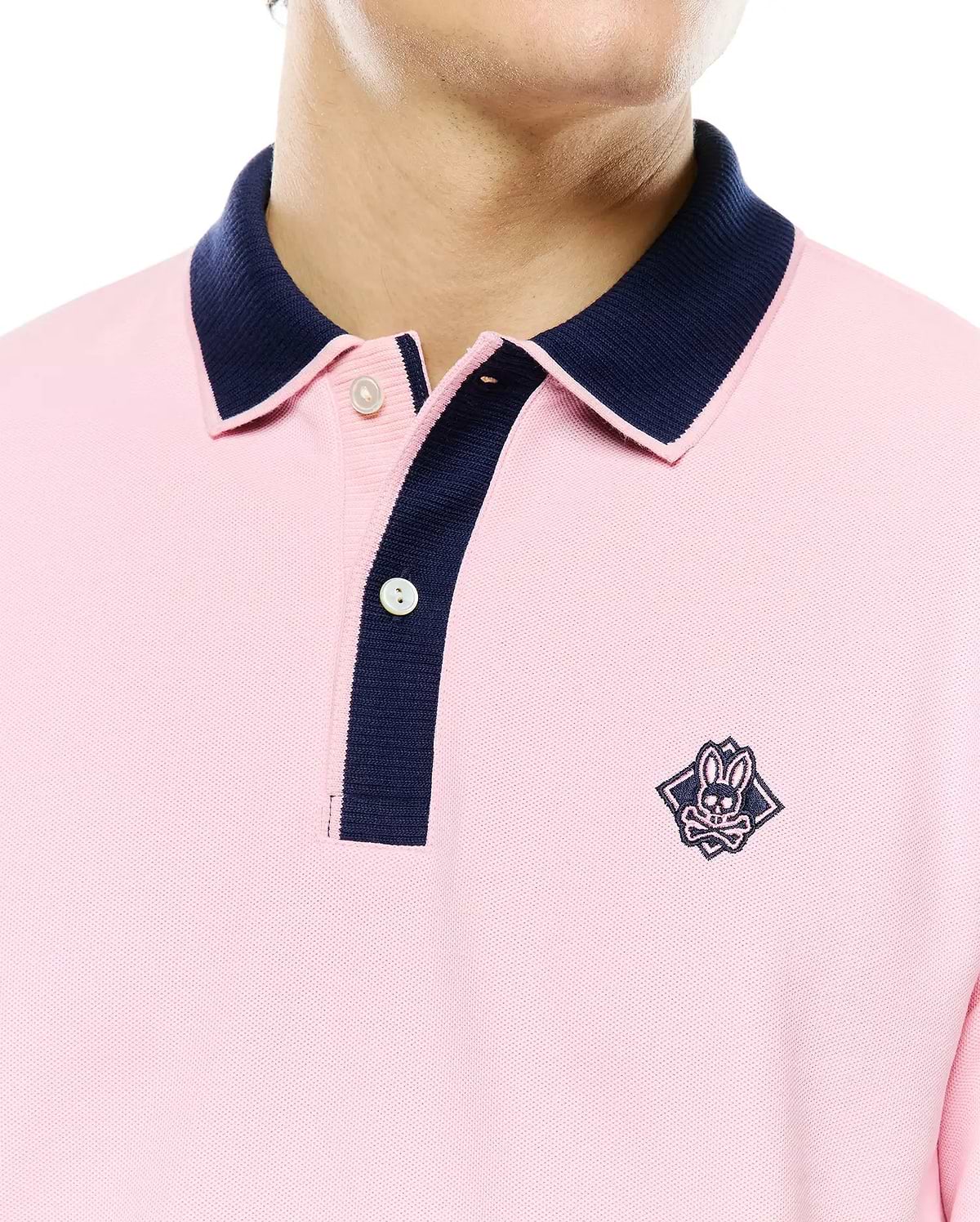 Mens Robin Pique Polo in pink pique fabric with a classic fit, featuring a navy blue contrast collar and placket, and an embroidered Psycho Bunny skull logo on the left chest.