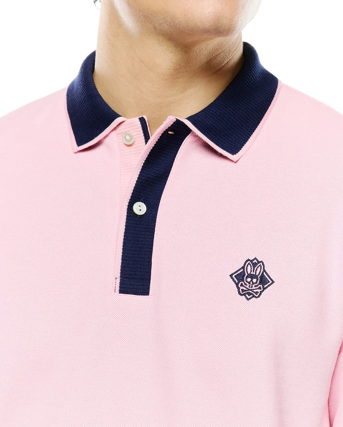 Mens Robin Pique Polo in pink pique fabric with a classic fit, featuring a navy blue contrast collar and placket, and an embroidered Psycho Bunny skull logo on the left chest.