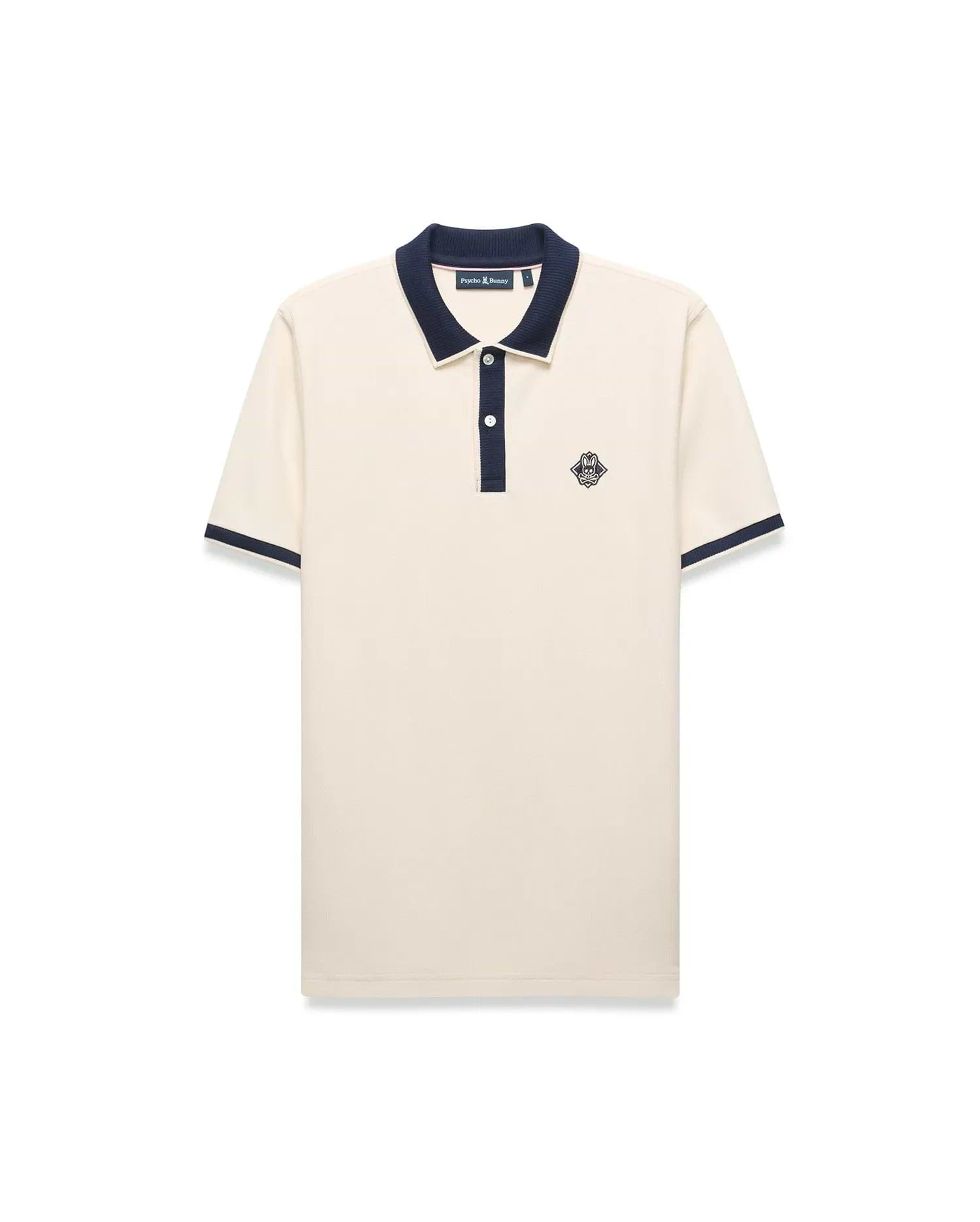 Mens Robin Pique Polo, a classic fit cream pique polo with navy blue ribbed collar, two-button placket, cuffs, and an embroidered Psycho Bunny skull logo on the left chest.