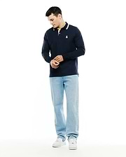 Men's Grover Pique Longsleeve Polo in navy, featuring a classic fit, pique texture, striped collar with cream and light blue, and a small embroidered white Psycho Bunny skull logo on the left chest. (4)