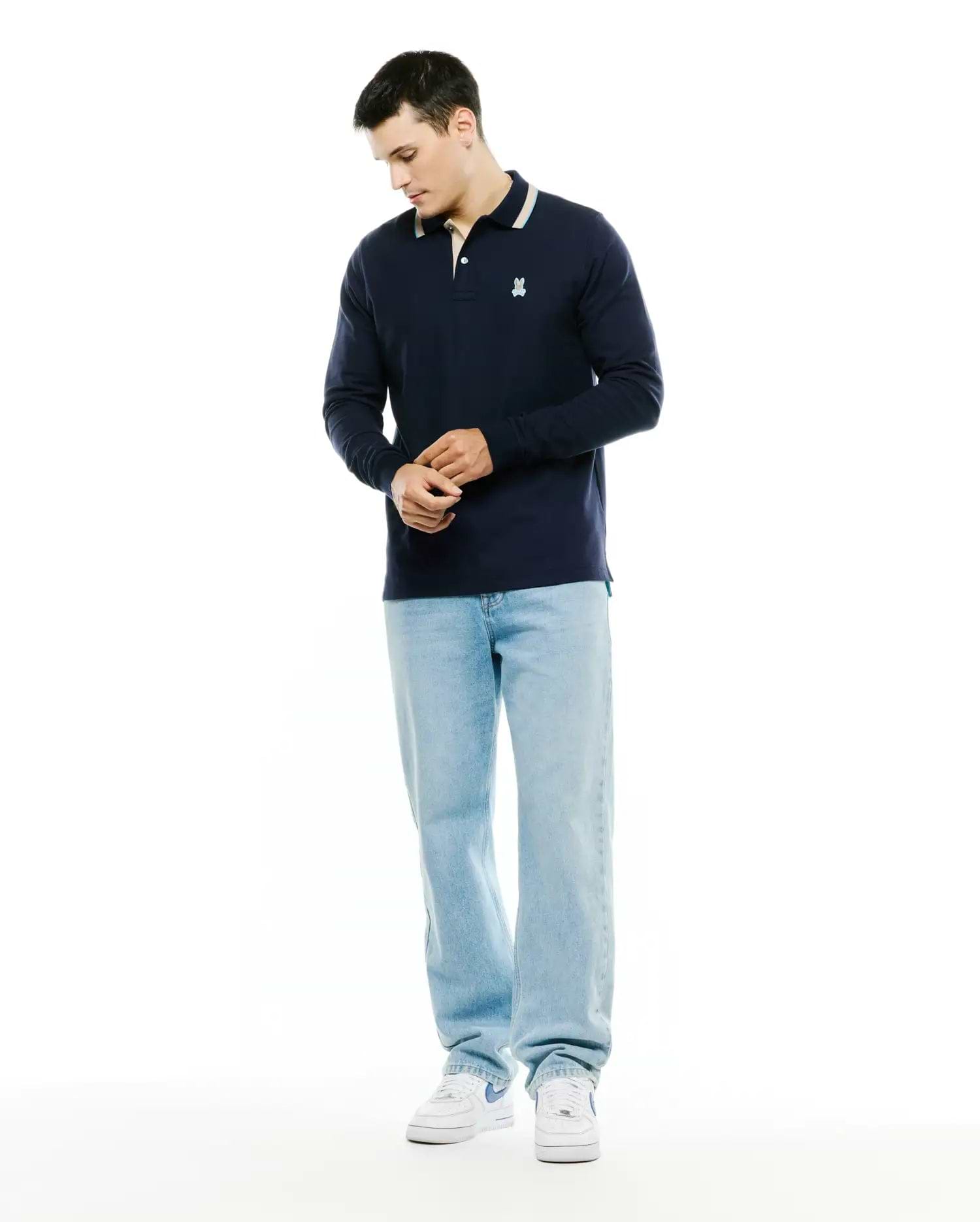 Men's Grover Pique Longsleeve Polo in navy, featuring a classic fit, pique texture, striped collar with cream and light blue, and a small embroidered white Psycho Bunny skull logo on the left chest. (4)