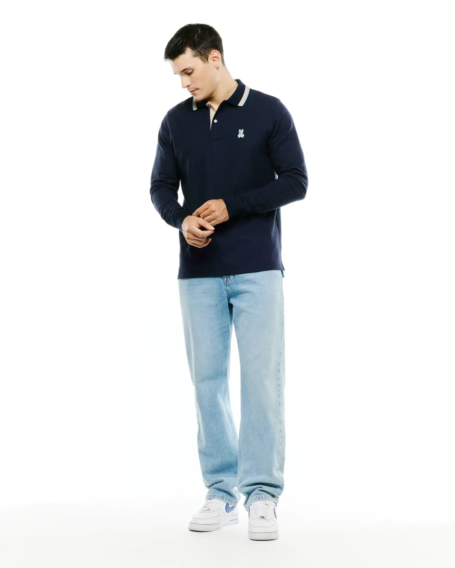 Men's Grover Pique Longsleeve Polo in navy, featuring a classic fit, pique texture, striped collar with cream and light blue, and a small embroidered white Psycho Bunny skull logo on the left chest. (4)