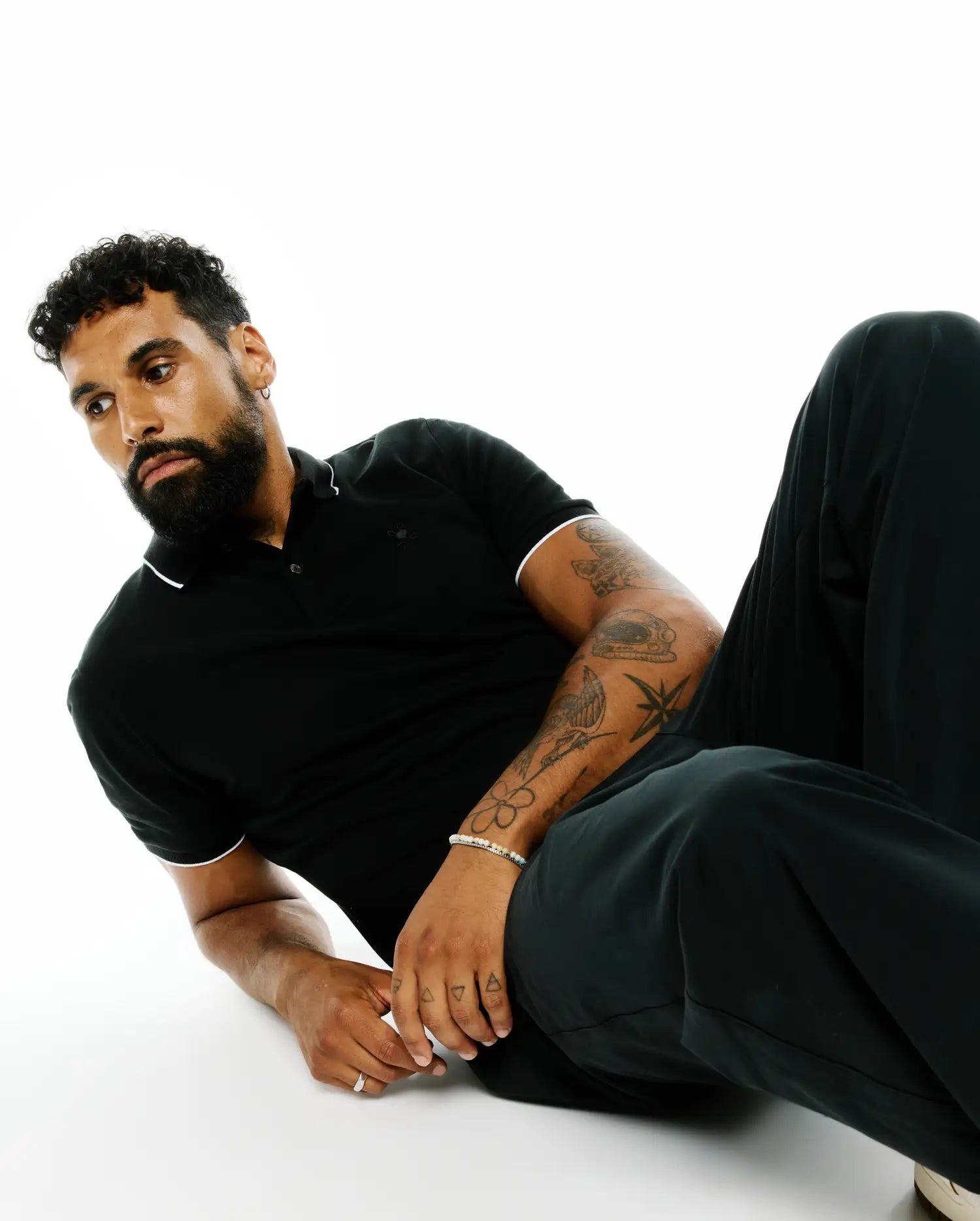 Mens Ringston Pique Polo in black, featuring a classic fit, pique fabric, white tipping on the collar and sleeves, and a small embroidered Psycho Bunny skull logo on the left chest.