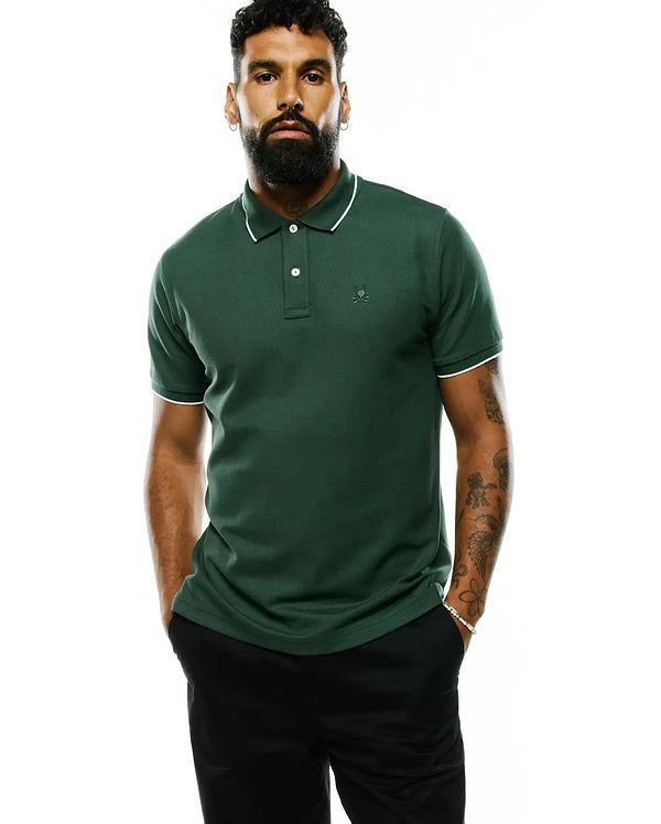 Mens Ringston Pique Polo in dark green, featuring a classic fit, pique fabric, white tipped collar and cuffs, and a small embroidered Psycho Bunny skull logo on the left chest.