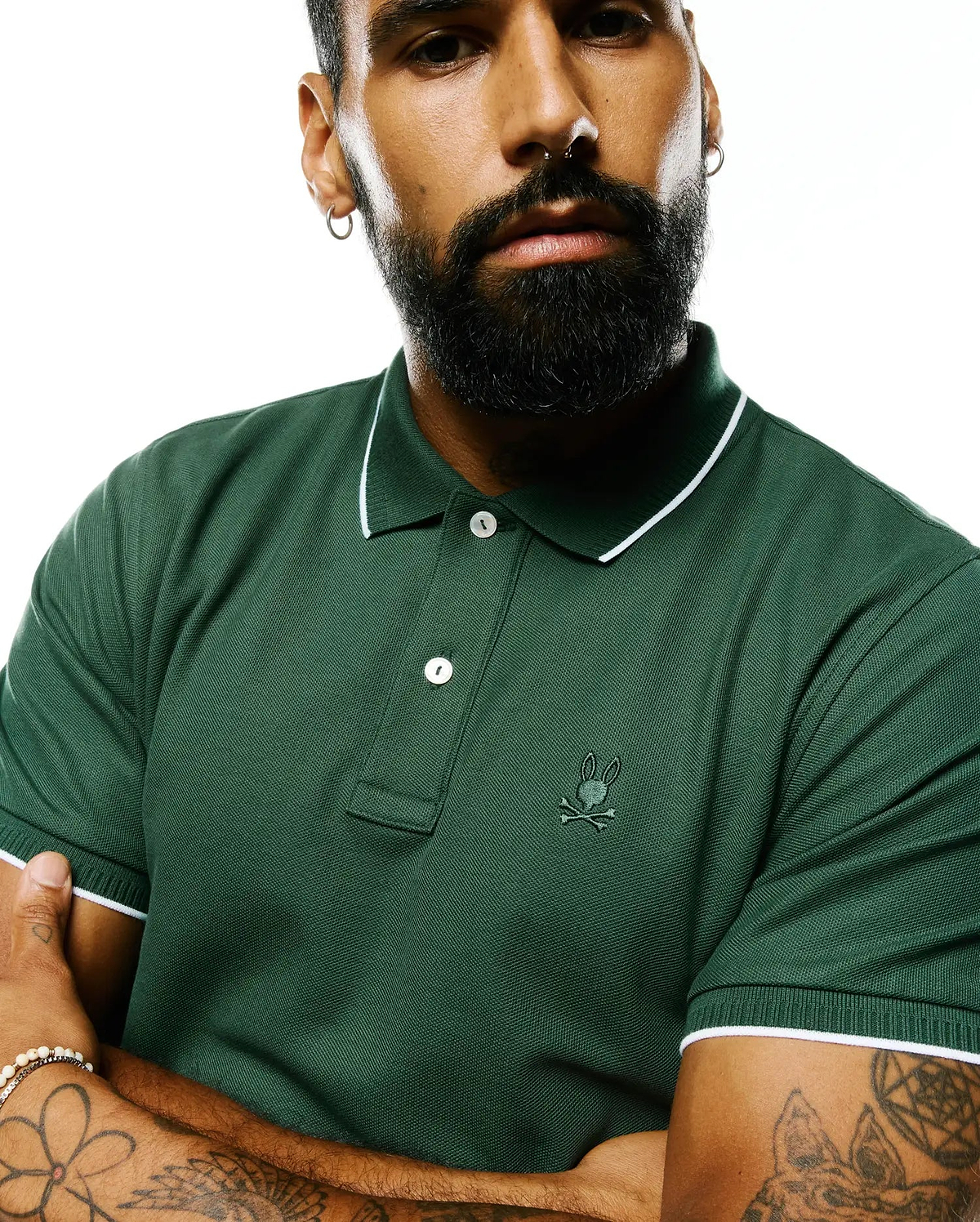 Mens Ringston Pique Polo in forest green pique knit, featuring a classic fit, white tipping on the ribbed collar and cuffs, two white buttons, and a small embroidered Psycho Bunny skull logo on the left chest.