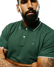 Mens Ringston Pique Polo in forest green pique knit, featuring a classic fit, white tipping on the ribbed collar and cuffs, two white buttons, and a small embroidered Psycho Bunny skull logo on the left chest.