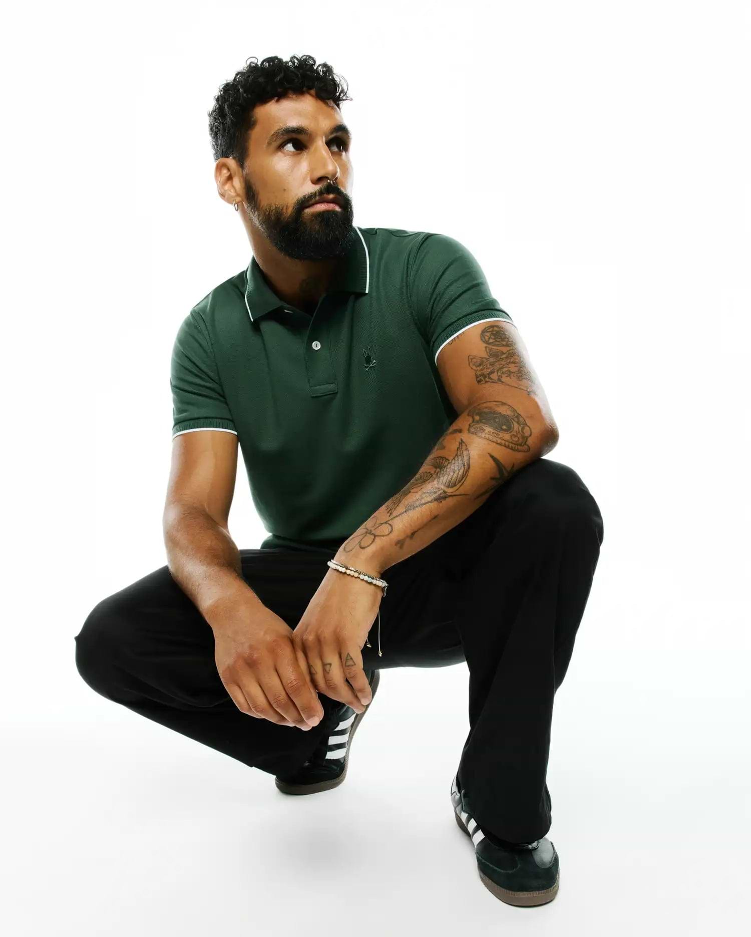 Mens Ringston Pique Polo in dark green, featuring a classic fit, pique knit fabric, white tipping on the collar and cuffs, and a small embroidered Psycho Bunny skull logo on the left chest.