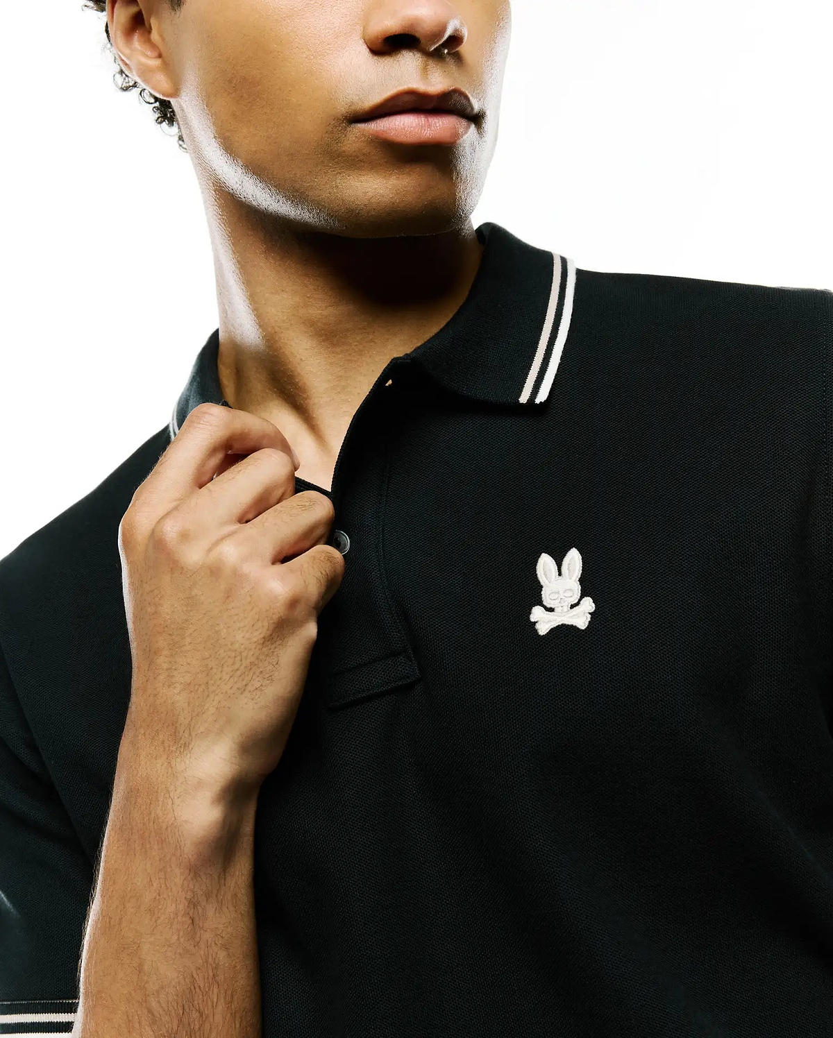 Mens Atley Pique Polo, black classic fit pique polo with white double-striped collar and cuffs, featuring a small embroidered white Psycho Bunny skull logo on the left chest. (2)