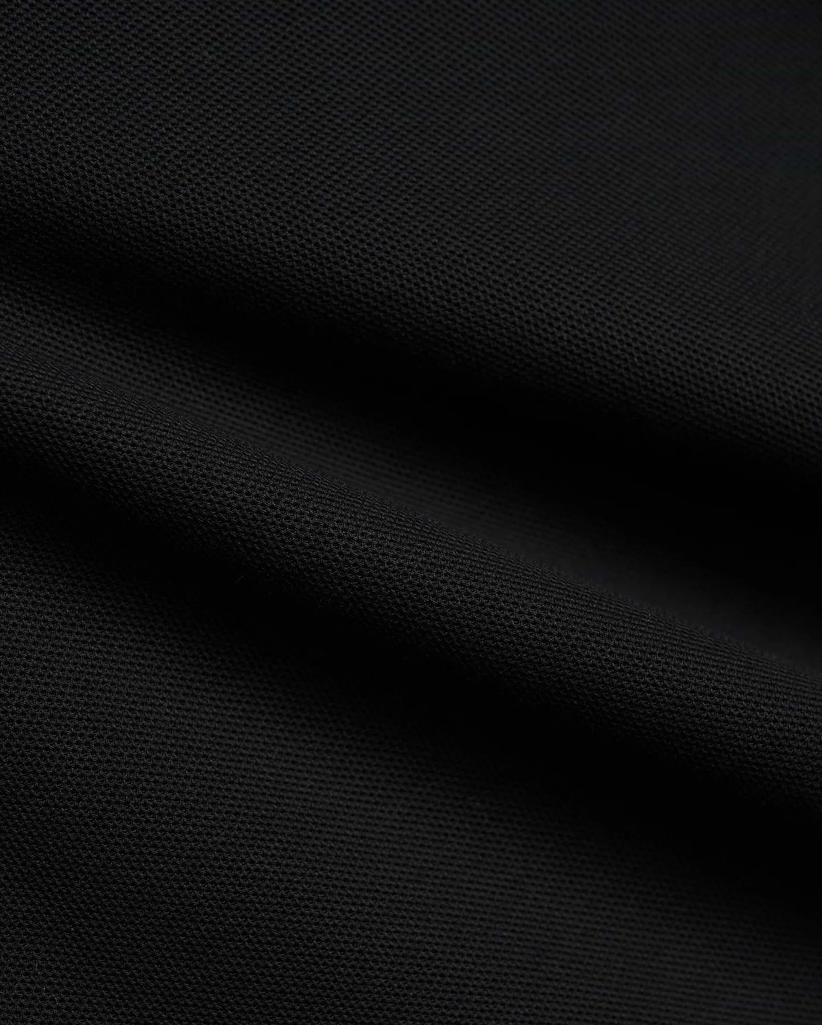 Psycho Bunny Mens Atley Pique Polo in deep black, showcasing the premium, breathable textured pique fabric with subtle folds, perfect for sophisticated streetwear. (6)