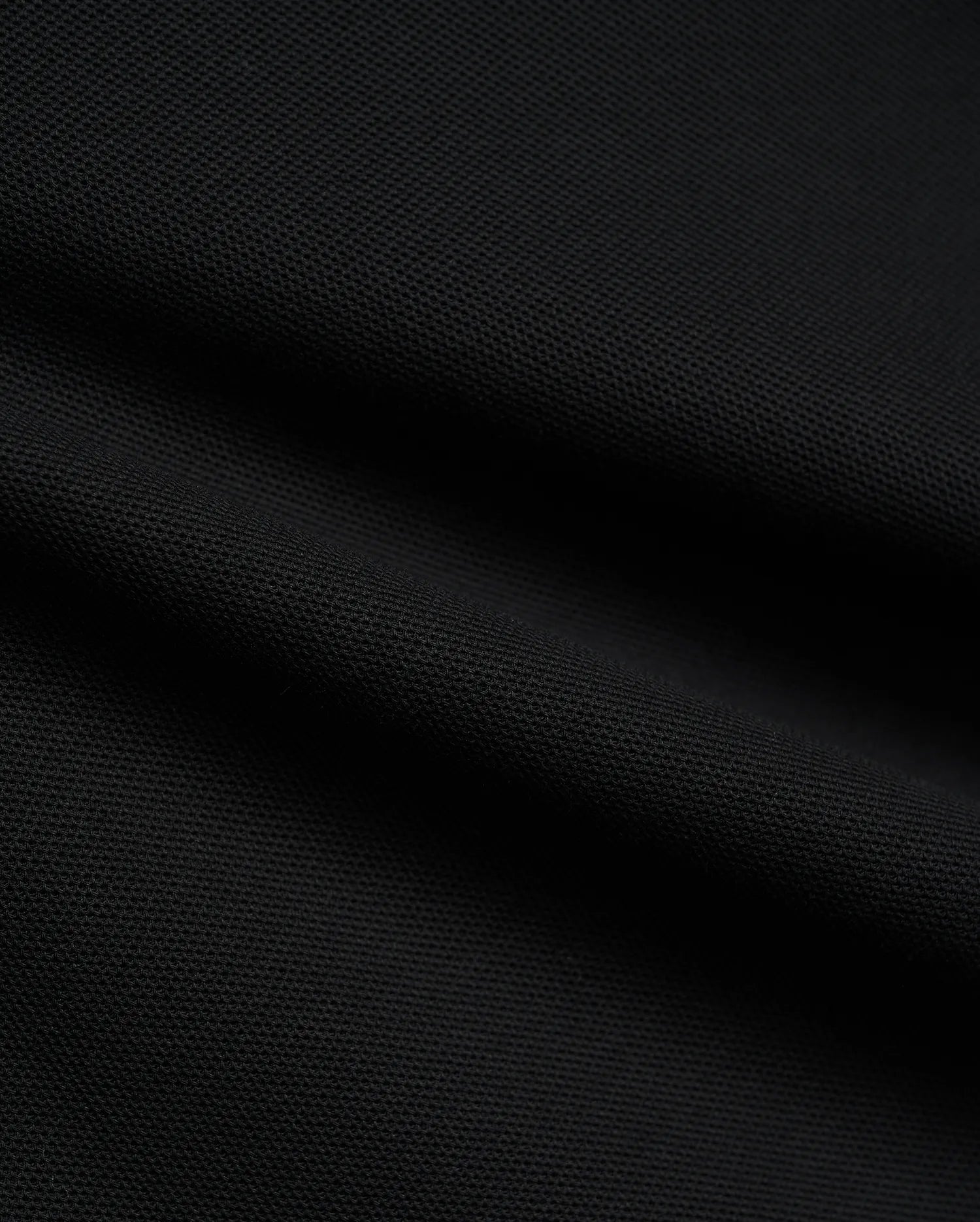 Psycho Bunny Mens Atley Pique Polo in deep black, showcasing the premium, breathable textured pique fabric with subtle folds, perfect for sophisticated streetwear. (6)