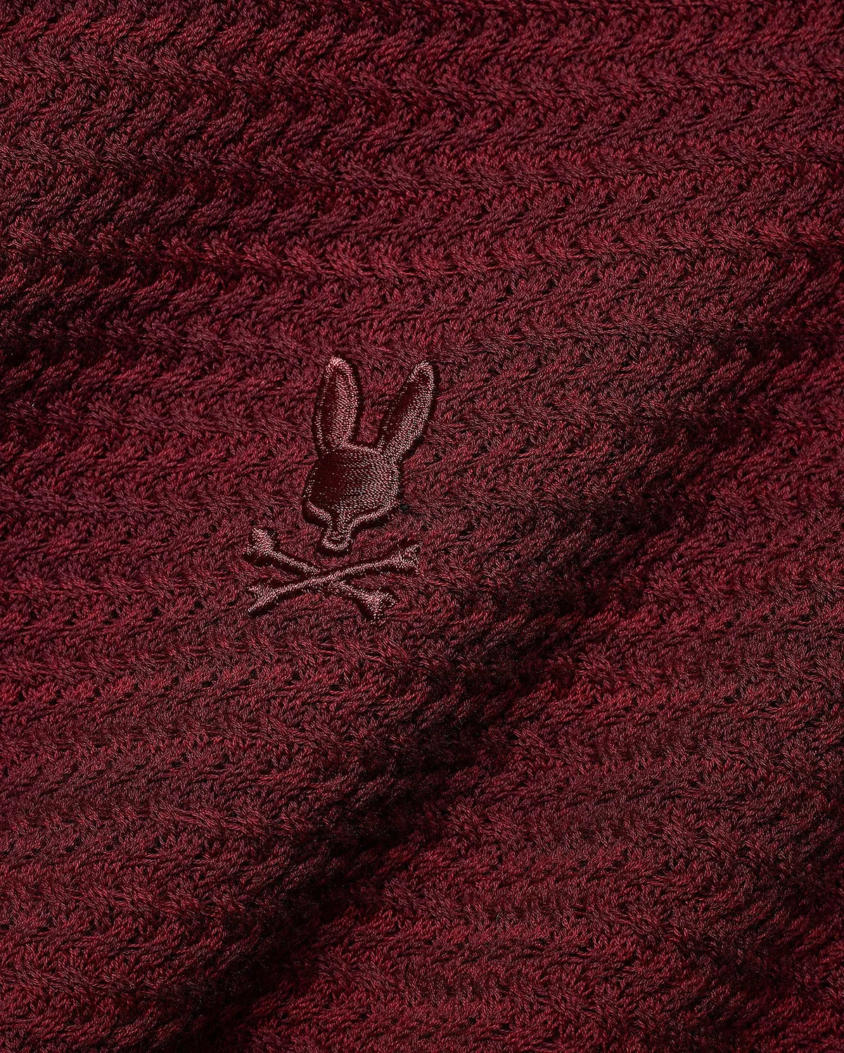 Men's Devon Braided Knit Polo in deep burgundy, featuring a rich braided knit texture and a small, tonal embroidered Psycho Bunny skull logo on the chest. (6)
