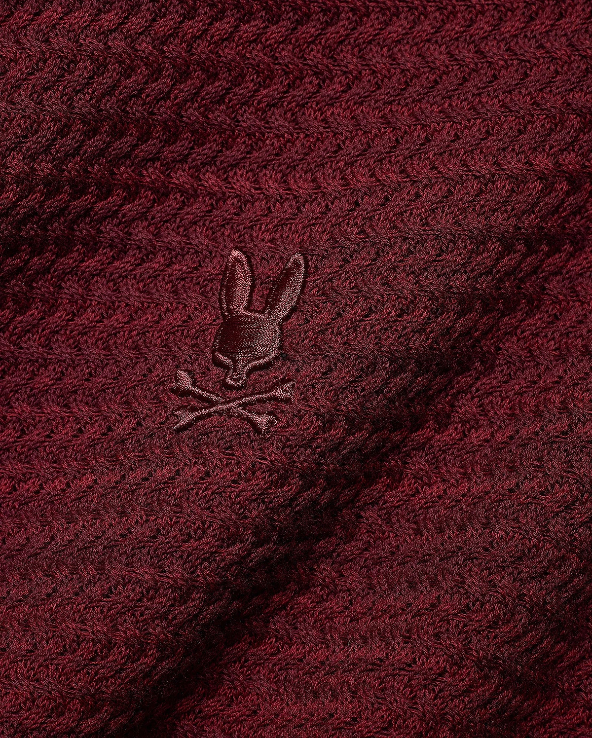 Men's Devon Braided Knit Polo in deep burgundy, featuring a rich braided knit texture and a small, tonal embroidered Psycho Bunny skull logo on the chest. (6)