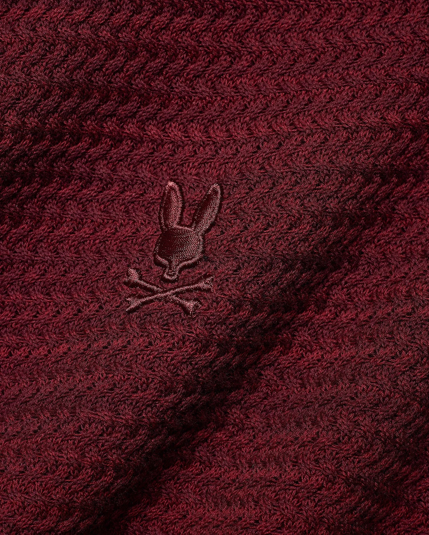 Men's Devon Braided Knit Polo in deep burgundy, featuring a rich braided knit texture and a small, tonal embroidered Psycho Bunny skull logo on the chest. (6)