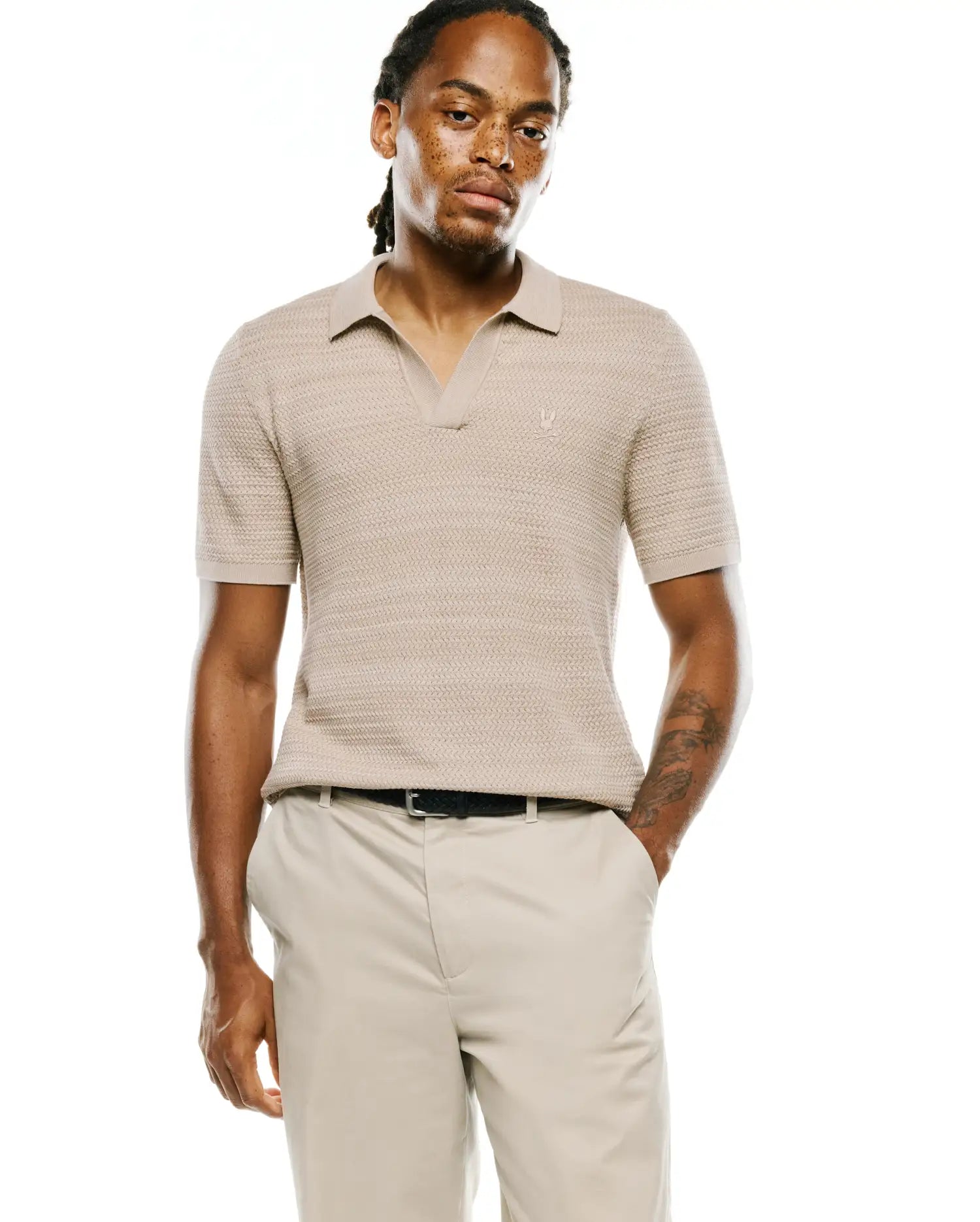 Mens Devon Braided Stitch Knit Polo in beige, featuring a classic fit, open collar, and a small embroidered Psycho Bunny skull logo on the left chest.