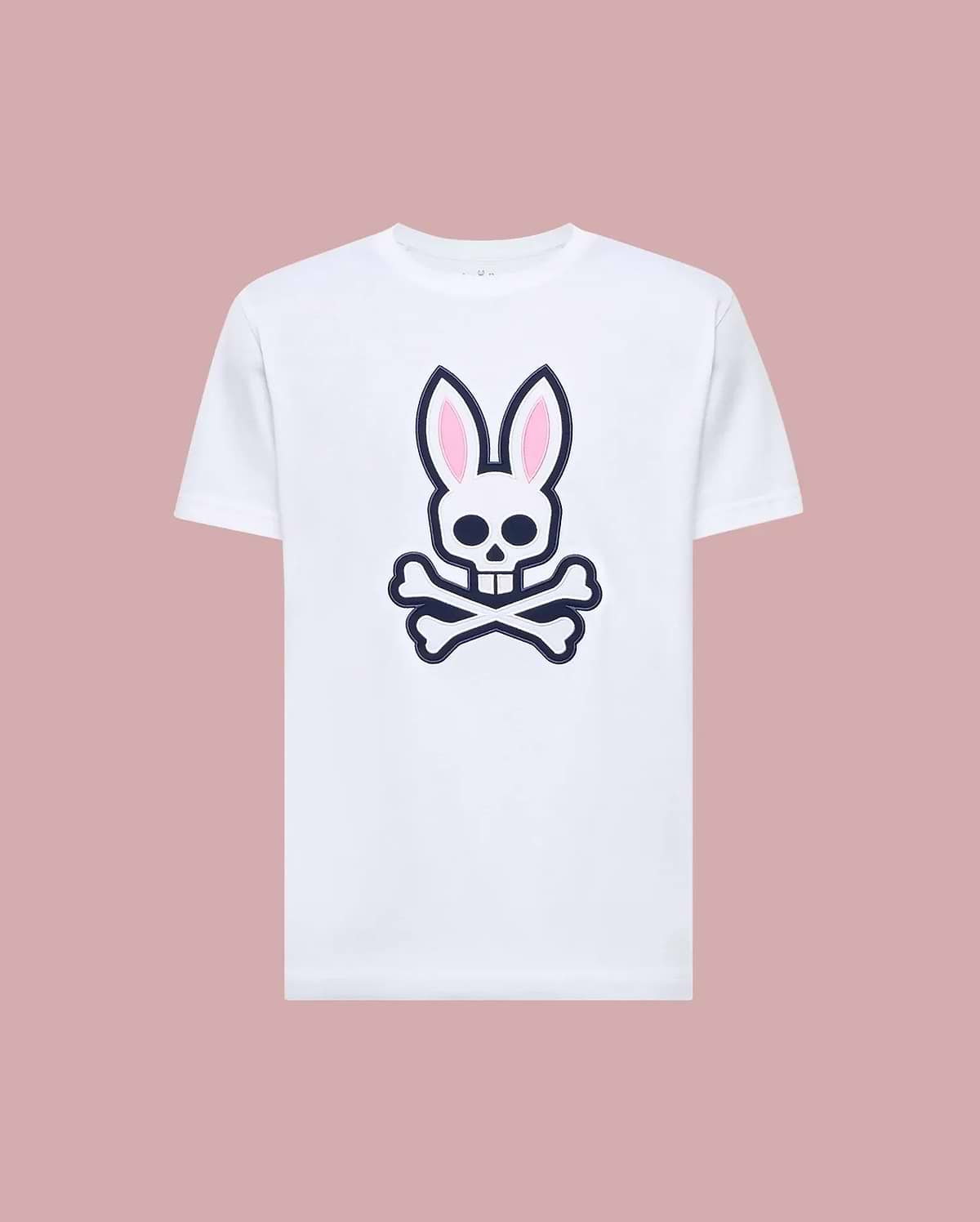 The Psycho Bunny MENS ARCHIVE BUNNY GRAPHIC TEE (MT0200031) is a white Pima cotton t-shirt featuring a large skull with bunny ears and crossbones graphic on the front, rib knit crewneck, shown against a muted pink background. (1)