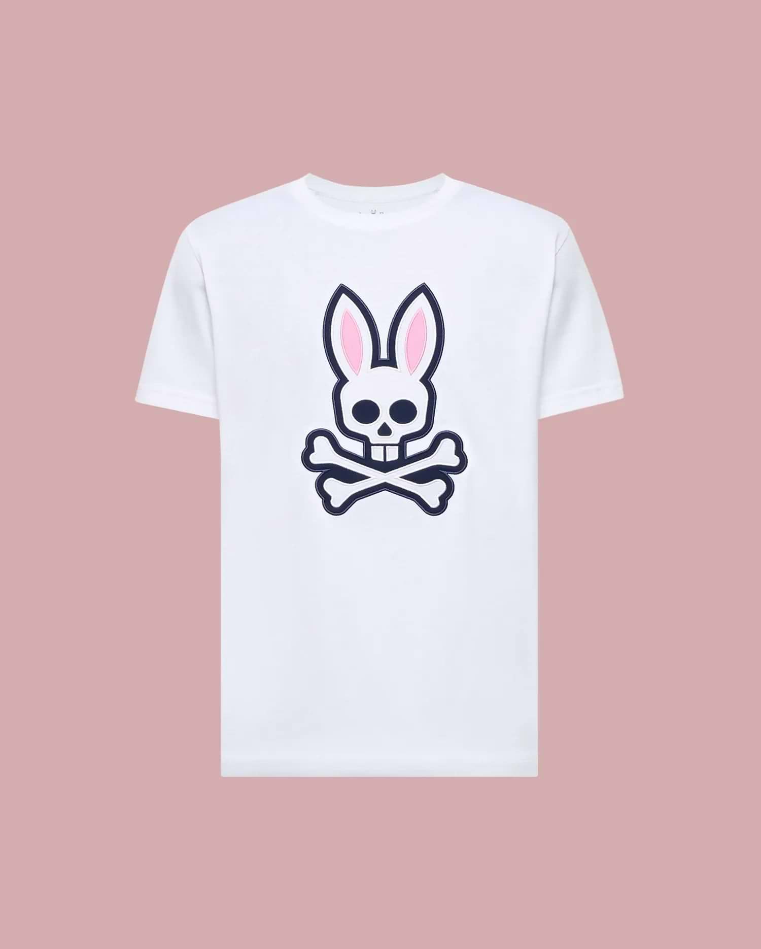 The Psycho Bunny MENS ARCHIVE BUNNY GRAPHIC TEE (MT0200031) is a white Pima cotton t-shirt featuring a large skull with bunny ears and crossbones graphic on the front, rib knit crewneck, shown against a muted pink background. (1)