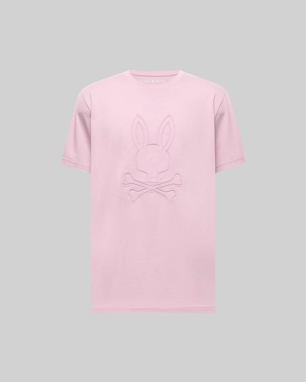 The Psycho Bunny MENS REMY GRAPHIC TEE (MT0200059) is a light pink Pima cotton short-sleeve tee with an embossed bunny logo above two crossed bones on the front, shown against a plain gray background. (1)