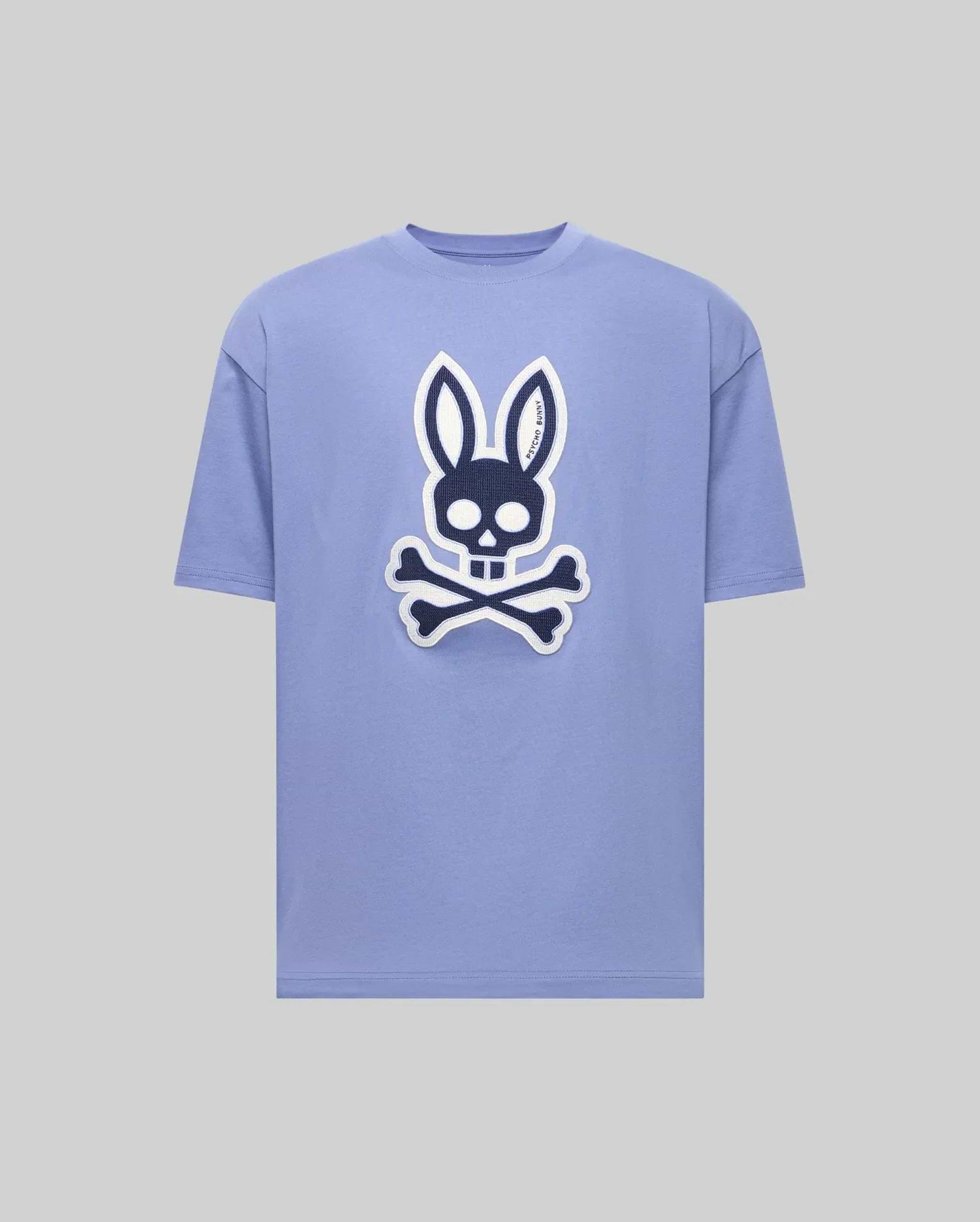 The Psycho Bunny MENS RYDER OVERSIZED FIT TEE (MT0200062) is a light purple premium tee with a bold black and white bunny skull and crossbones graphic on the front, shown against a plain gray background. (1)