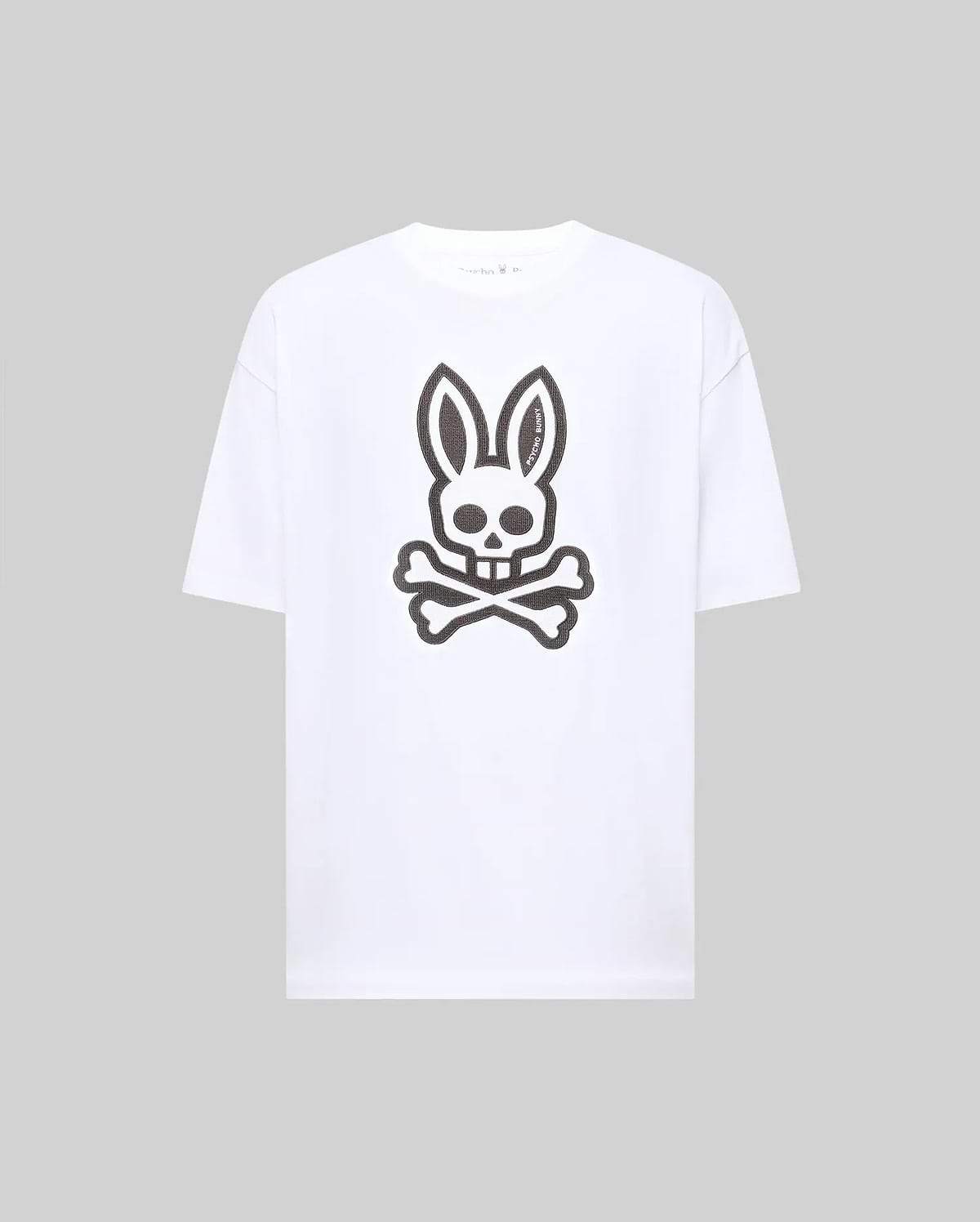 The Psycho Bunny MENS RYDER OVERSIZED FIT TEE (MT0200062) is a premium white Pima cotton T-shirt with an oversized fit, featuring a large black bunny skull and crossbones graphic on the front.
