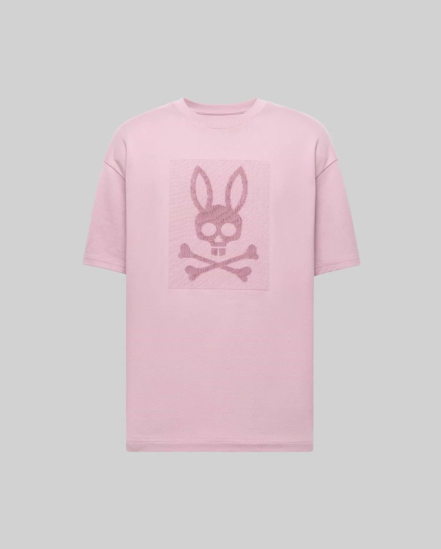 The Psycho Bunny MENS REECE OVERSIZED TEE (MT0200082) is a light pink, heavyweight jersey tee in a relaxed fit, featuring a centered skull with bunny ears above crossed bones on the chest against a plain gray background. (5)