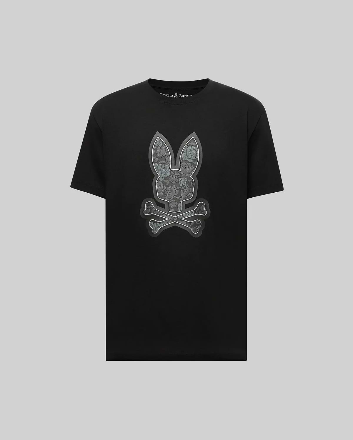 The Psycho Bunny MENS ROWEN BUNNY GRAPHIC TEE (MT0200101) features a large gray bunny face with crossed bones in graphic style, crafted from soft Pima cotton and set against a light gray background.
