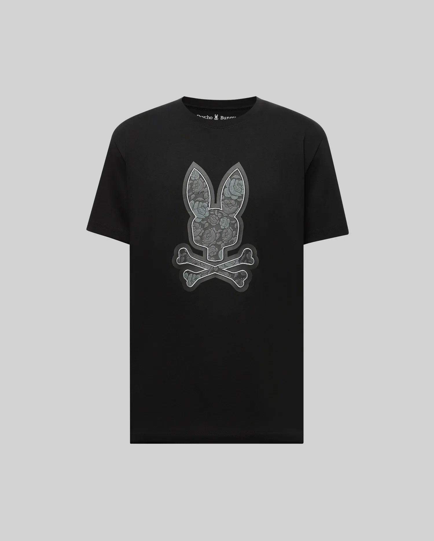The Psycho Bunny MENS ROWEN BUNNY GRAPHIC TEE (MT0200101) features a large gray bunny face with crossed bones in graphic style, crafted from soft Pima cotton and set against a light gray background.