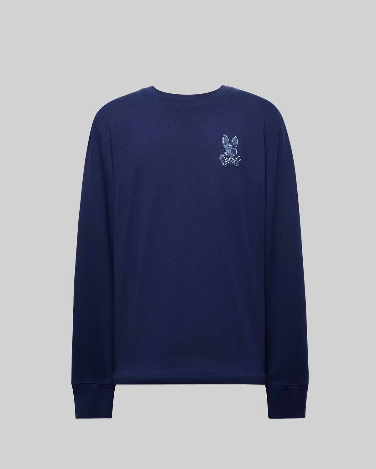 The Psycho Bunny MENS ROWEN GRAPHIC TEE (MT0200103) is a navy Pima cotton long sleeve shirt with a small embroidered rabbit and crossbones patch on the upper left chest, shown on a plain gray background.