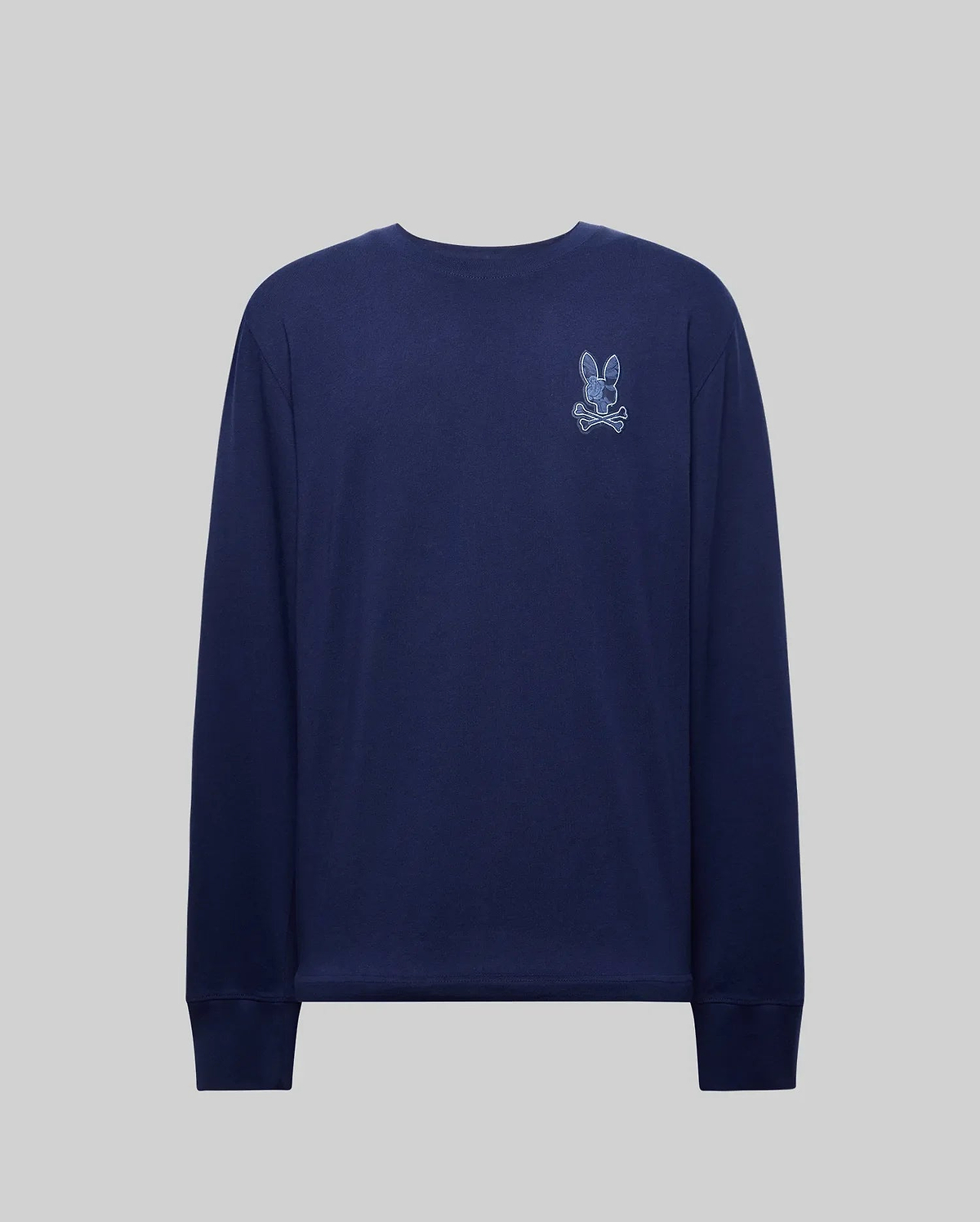 The Psycho Bunny MENS ROWEN GRAPHIC TEE (MT0200103) is a navy Pima cotton long sleeve shirt with a small embroidered rabbit and crossbones patch on the upper left chest, shown on a plain gray background.