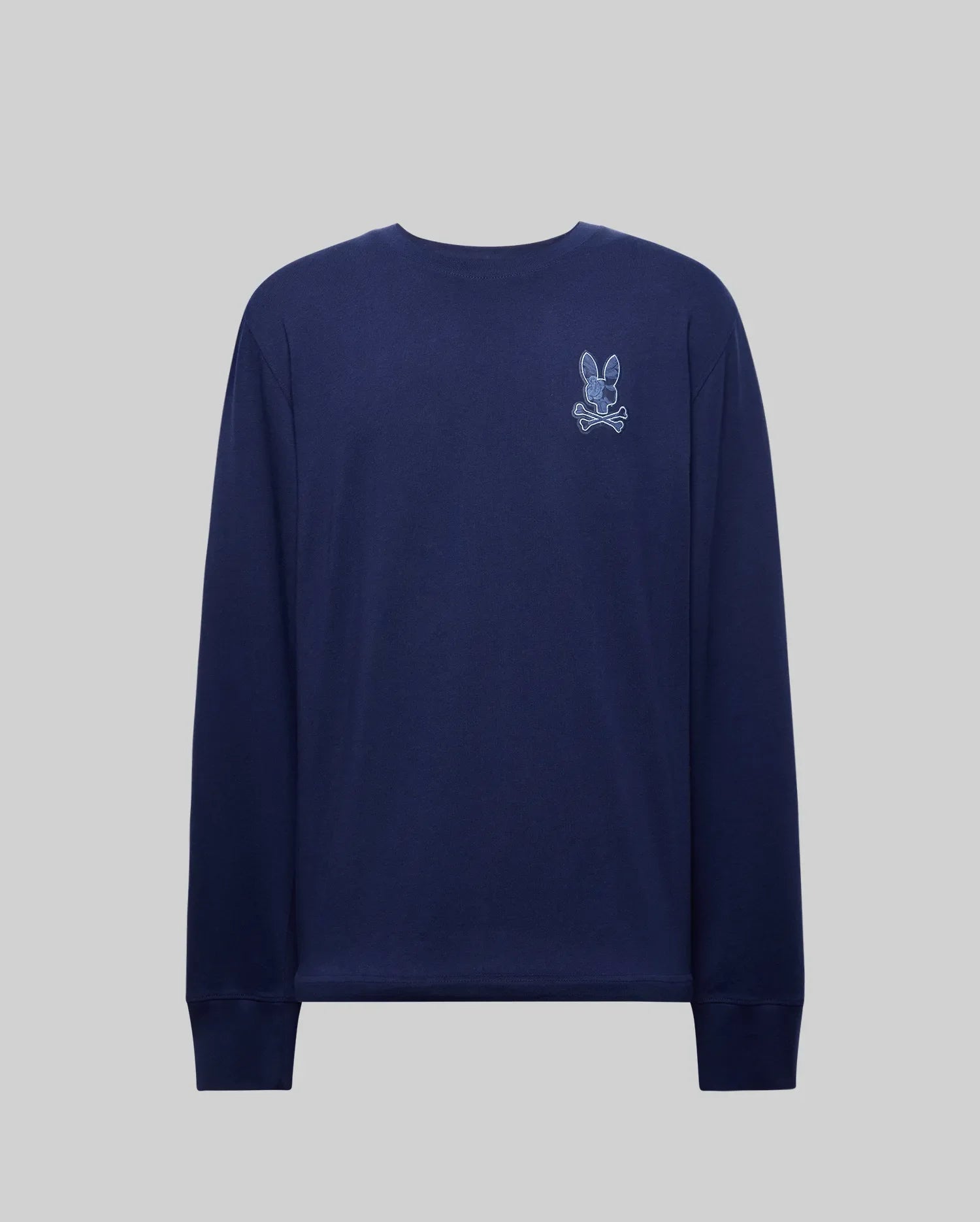 The Psycho Bunny MENS ROWEN GRAPHIC TEE (MT0200103) is a navy Pima cotton long sleeve shirt with a small embroidered rabbit and crossbones patch on the upper left chest, shown on a plain gray background.