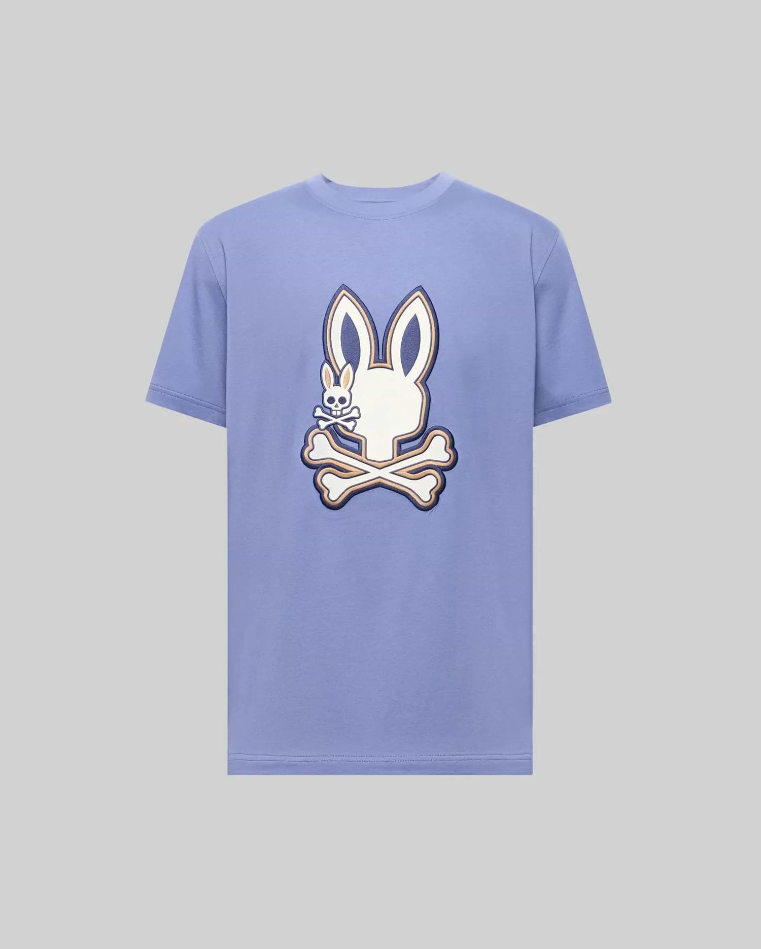 The Psycho Bunny MENS WADE GRAPHIC TEE (MT0200106) is a light purple 100% cotton shirt featuring a large white cartoon bunny head with crossbones on the front.