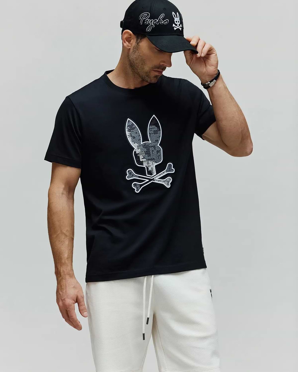 Mens Olivier Graphic Tee, a black premium jersey t-shirt with a classic fit, featuring a large, iconic white-outlined, textured grey Psycho Bunny skull and crossbones graphic on the chest. (4)