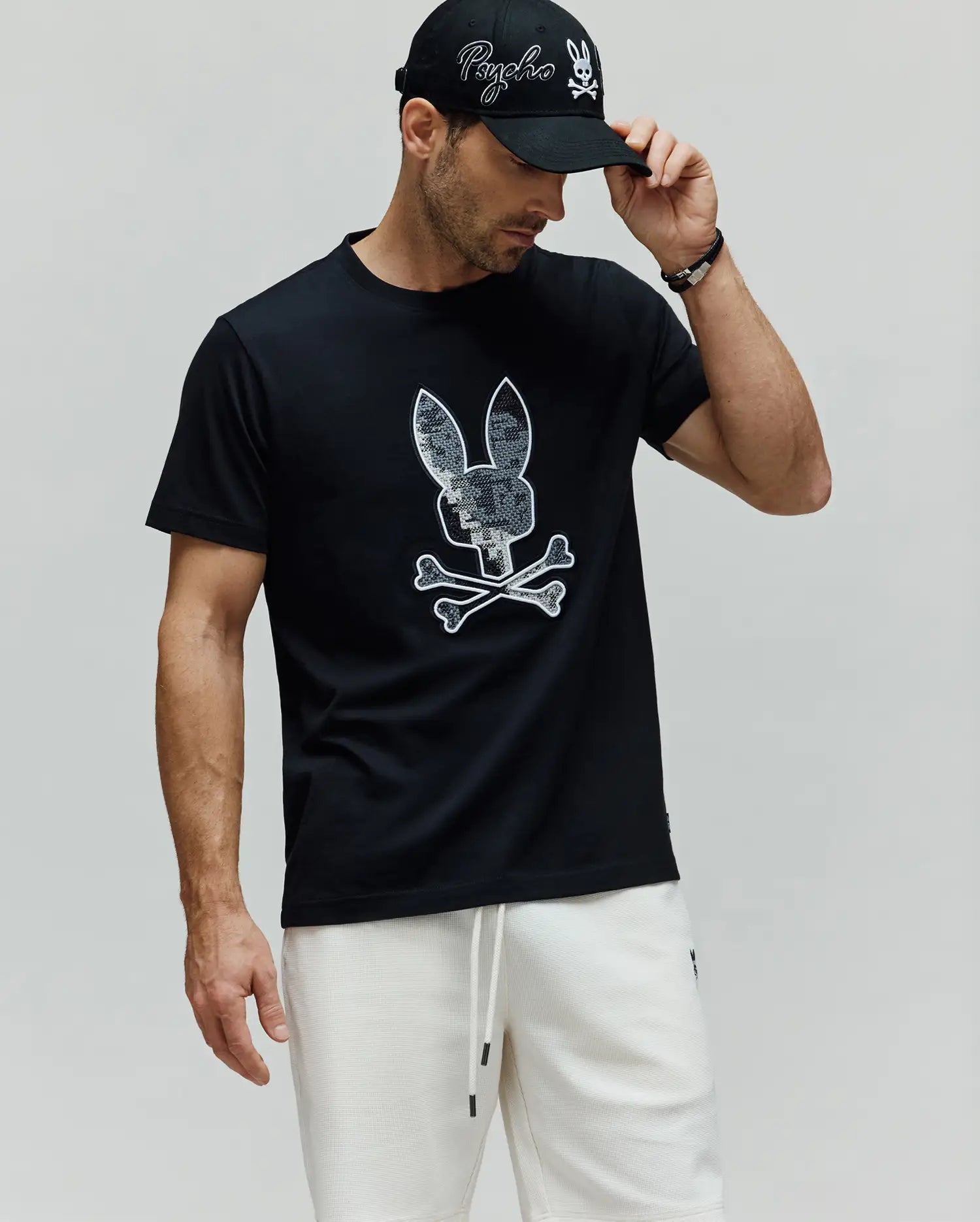 Mens Olivier Graphic Tee, a black premium jersey t-shirt with a classic fit, featuring a large, iconic white-outlined, textured grey Psycho Bunny skull and crossbones graphic on the chest. (4)