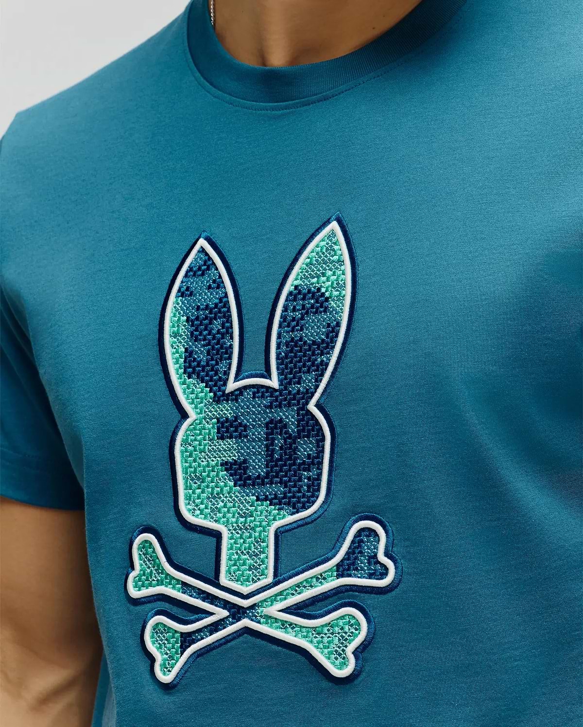 Mens Olivier Graphic Tee in teal, featuring a large central embroidered pixelated green and dark blue bunny skull logo with white outline on soft jersey knit fabric, classic fit. (3)