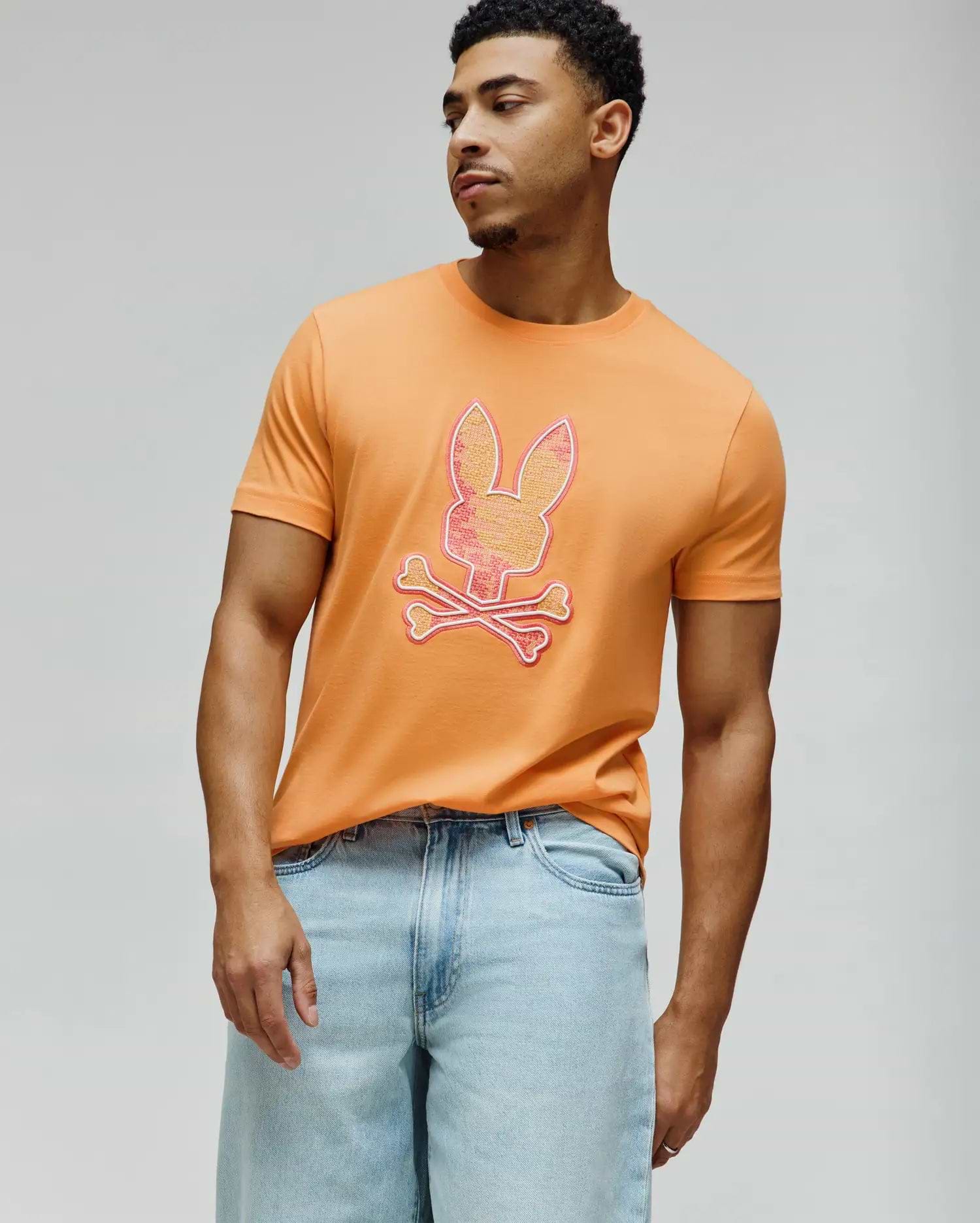 Mens Olivier Graphic Tee, vibrant orange classic fit jersey knit t-shirt featuring a large, central Psycho Bunny skull logo with a pink-to-yellow gradient and white outline. (2)