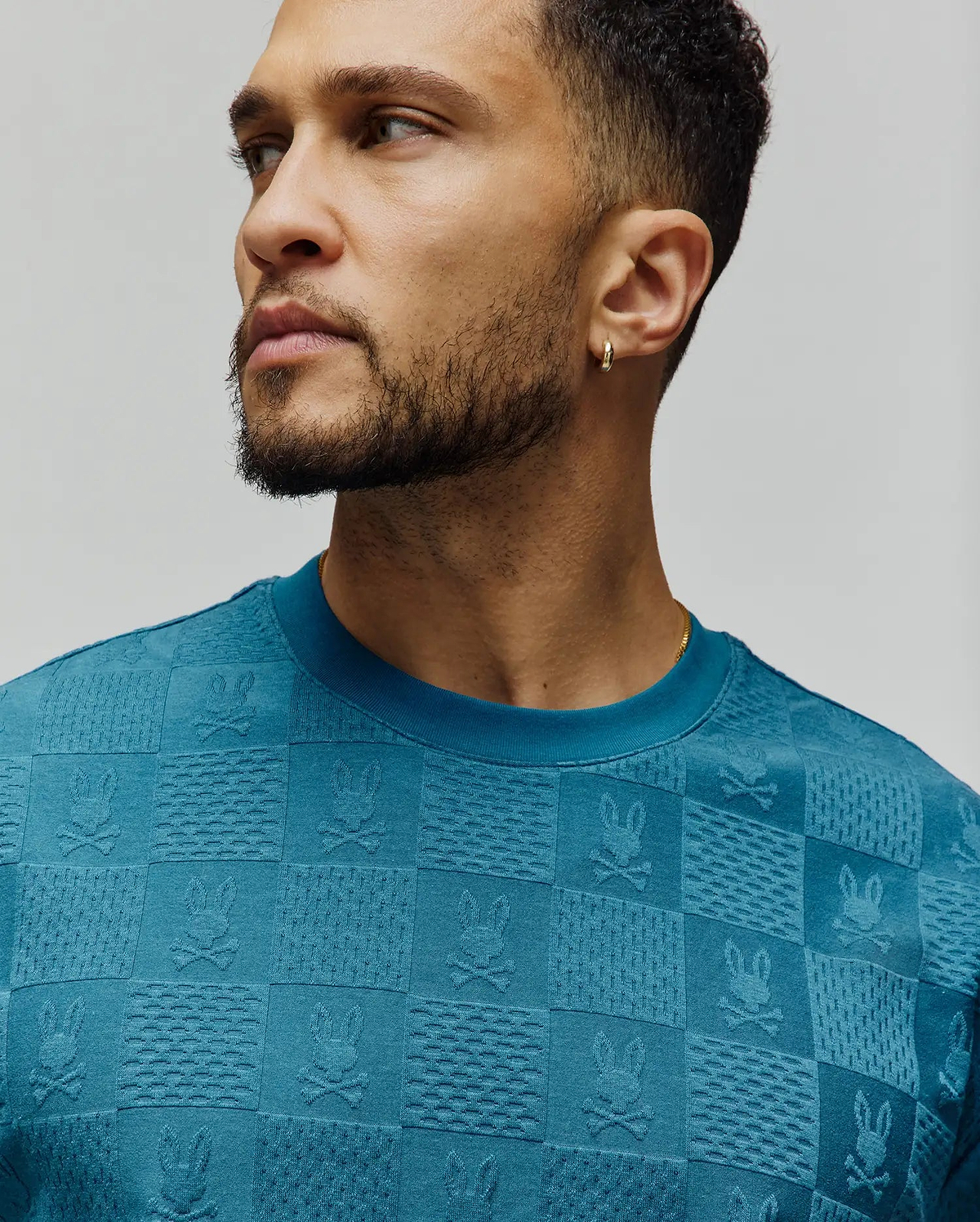 Mens Dustin Oversized Tee in teal, featuring an all-over jacquard checkerboard pattern with embossed Psycho Bunny skull logos and varied textured squares, in a soft knit. (3)