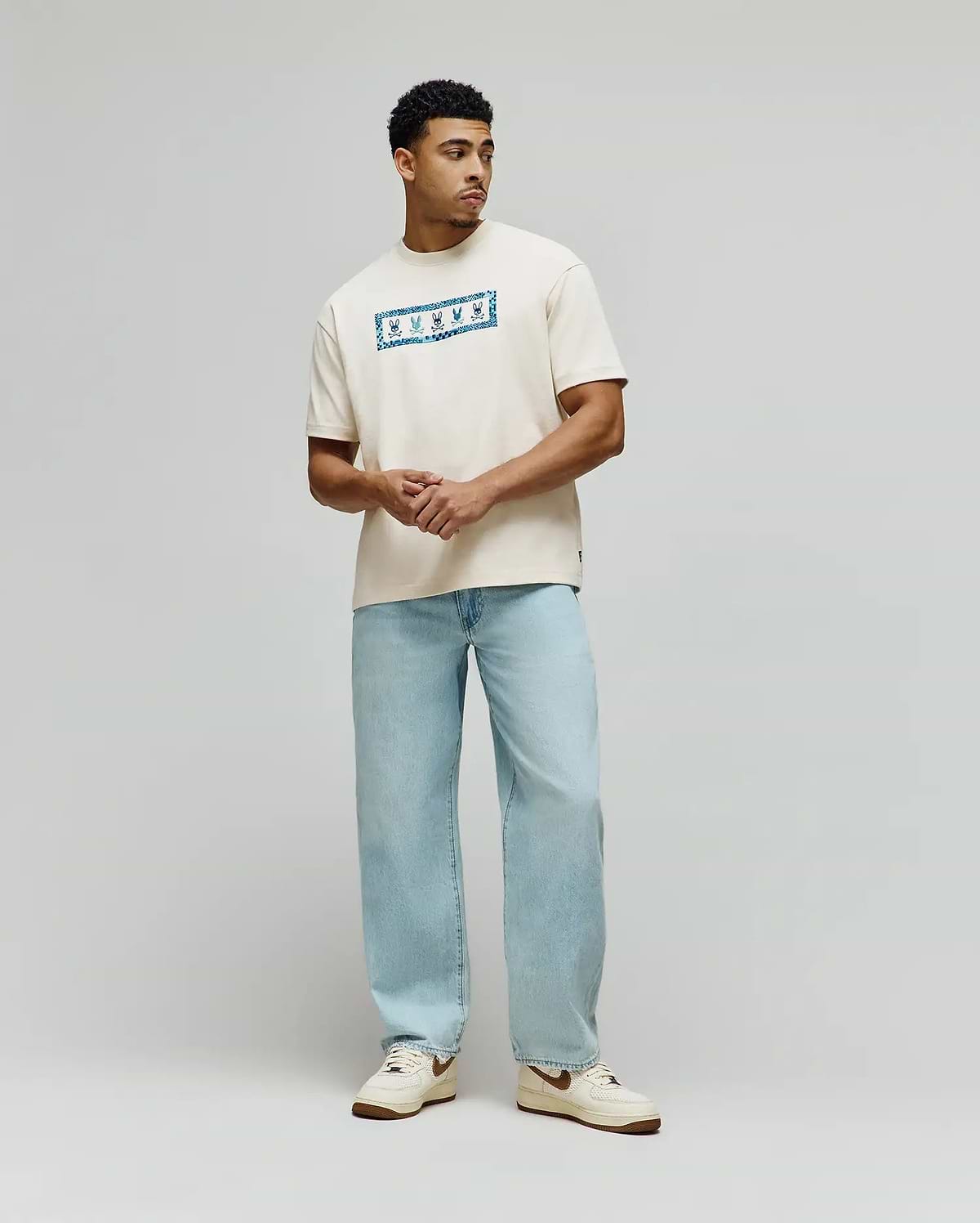 Mens Olivier Oversized Tee in cream jersey knit, featuring a prominent central chest graphic with a vibrant blue bandana-style pattern and white Psycho Bunny skull logos. (3)