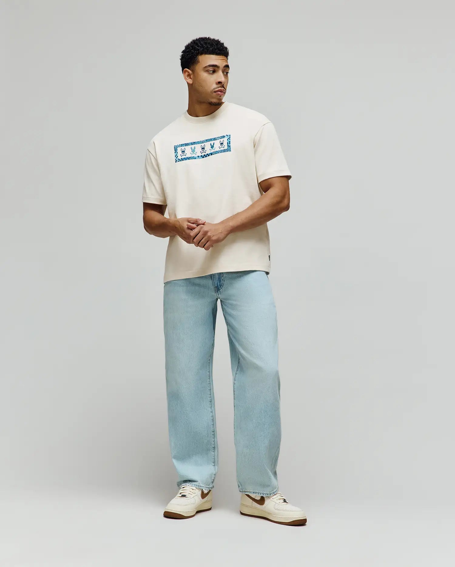 Mens Olivier Oversized Tee in cream jersey knit, featuring a prominent central chest graphic with a vibrant blue bandana-style pattern and white Psycho Bunny skull logos. (3)