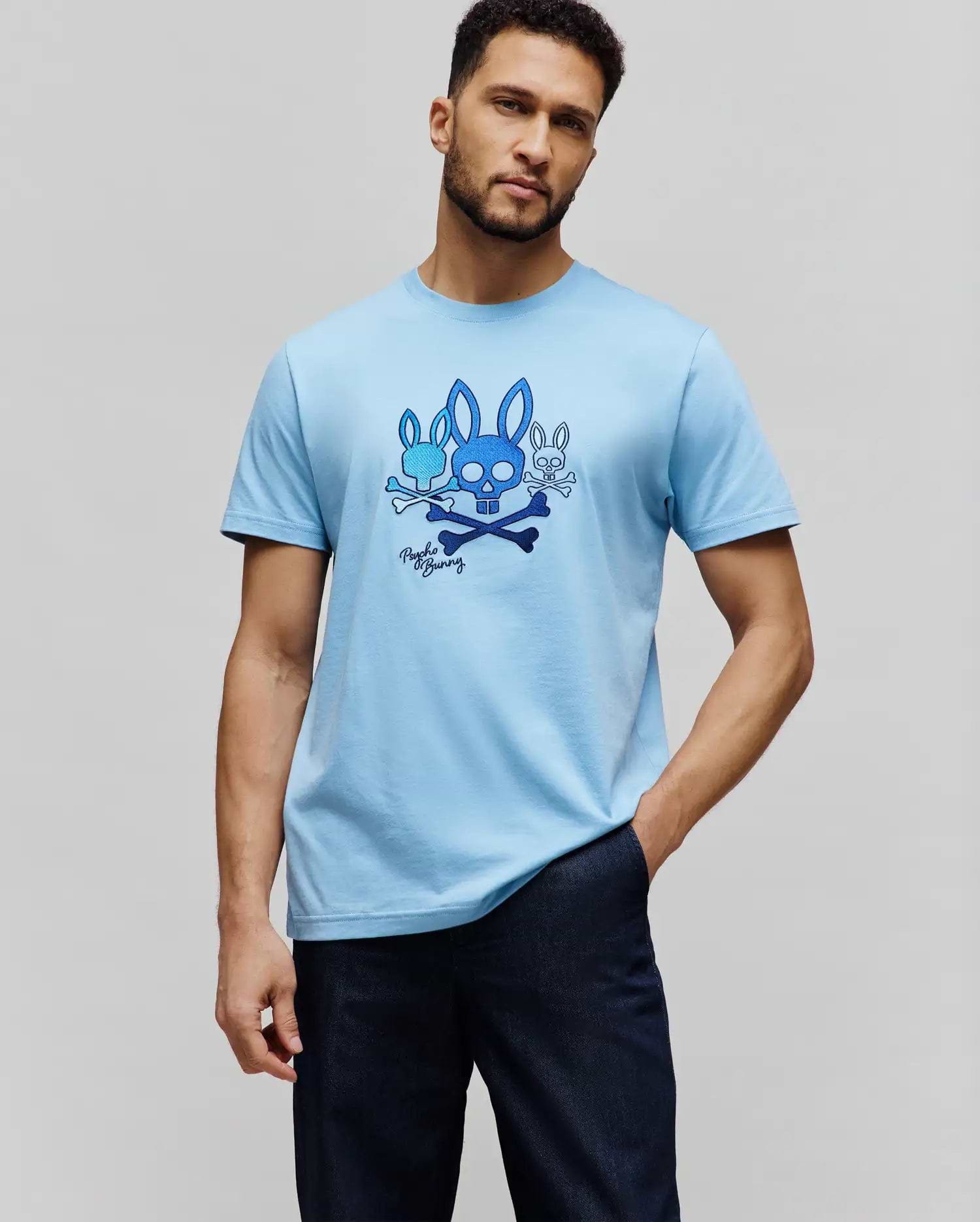 Mens Oscar Graphic Tee, light blue classic fit jersey knit t-shirt with a large central chest graphic featuring multiple blue Psycho Bunny skull logos, crossbones, and script. (5)